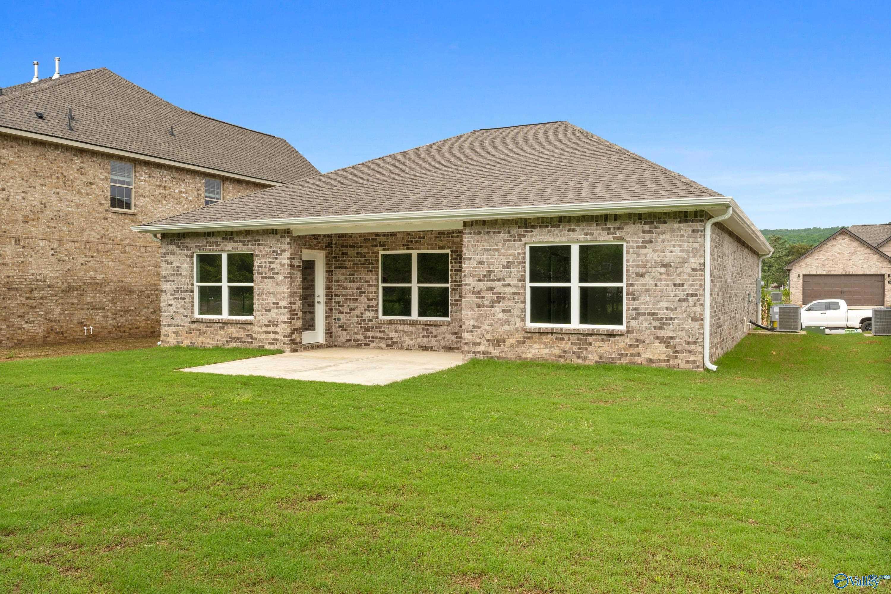 Modern brick single-story home with gabled roof, front porch, and green lawn in Jaguar Hills, Huntsville, Alabama - Davidson Homes The Asheville C