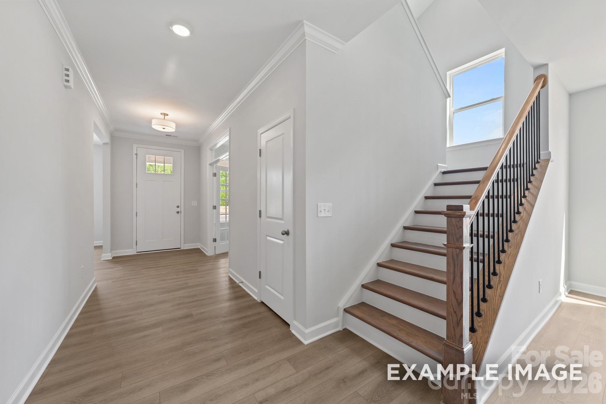 Bright foyer with wood-look flooring and staircase in The Magnolia B floor plan by Davidson Homes in Windgate, Mooresville.