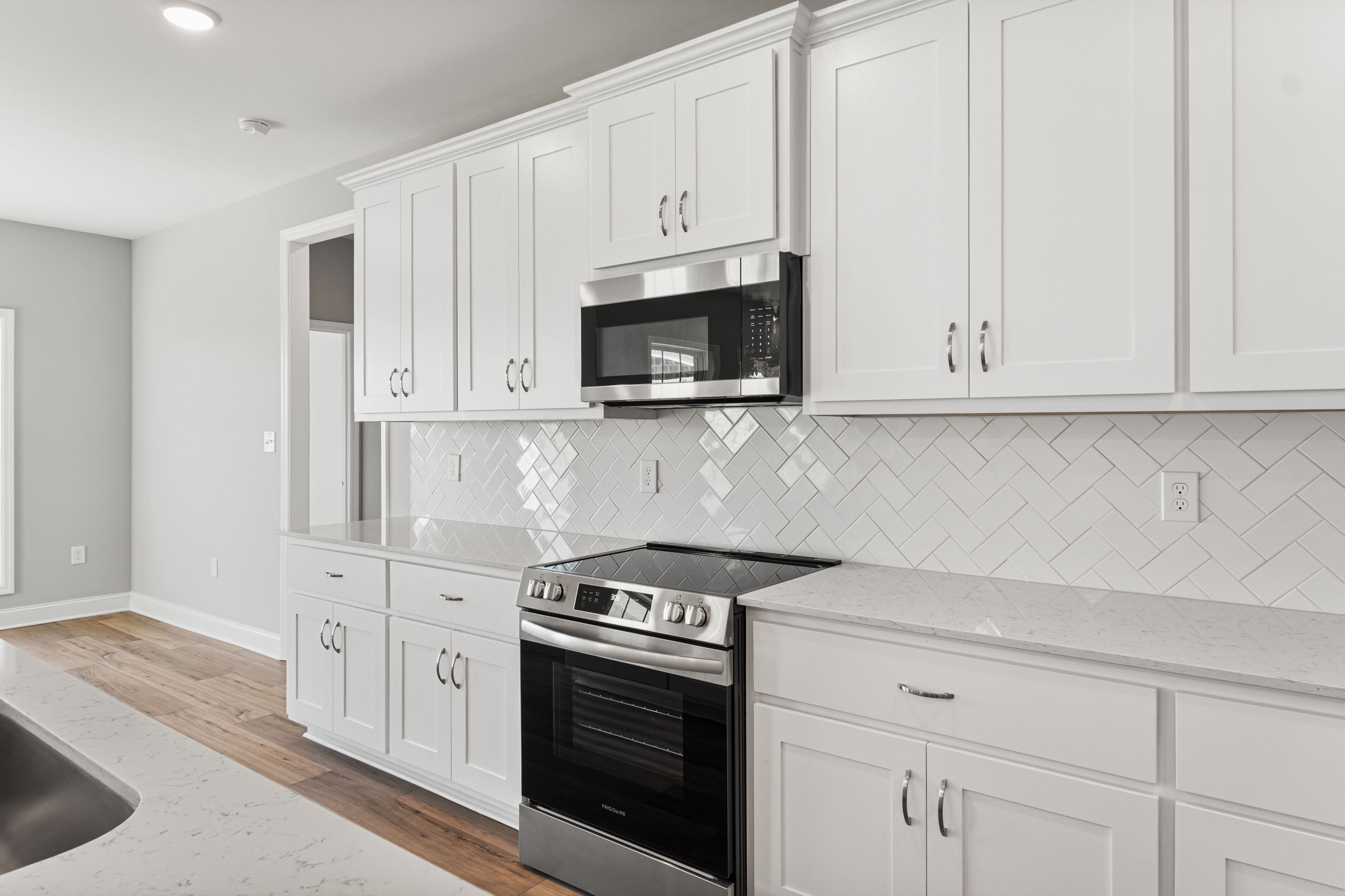 Modern Valencia kitchen featuring white shaker cabinets, herringbone subway tile backsplash, stainless steel appliances, quartz counters
