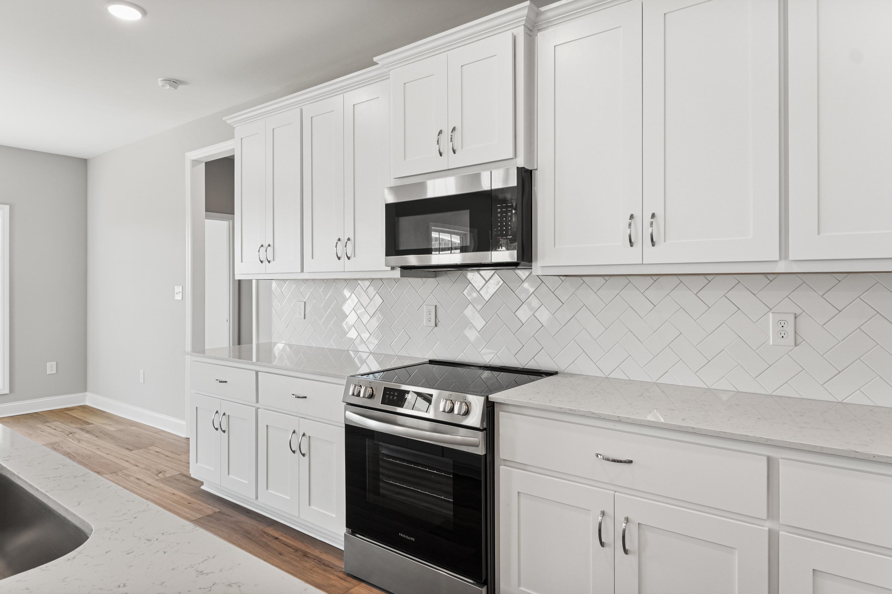 Modern Valencia kitchen featuring white shaker cabinets, herringbone subway tile backsplash, stainless steel appliances, quartz counters