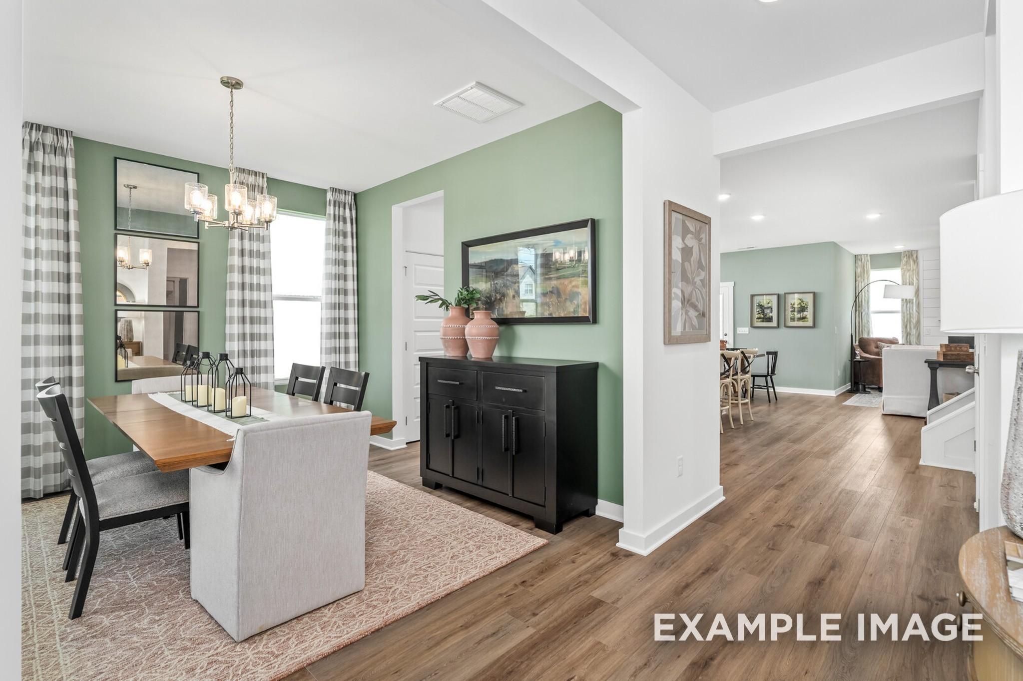Elegant dining room with sage green accent wall and hardwood floors in The Ash A floor plan at Woods Crossing, Gallatin.