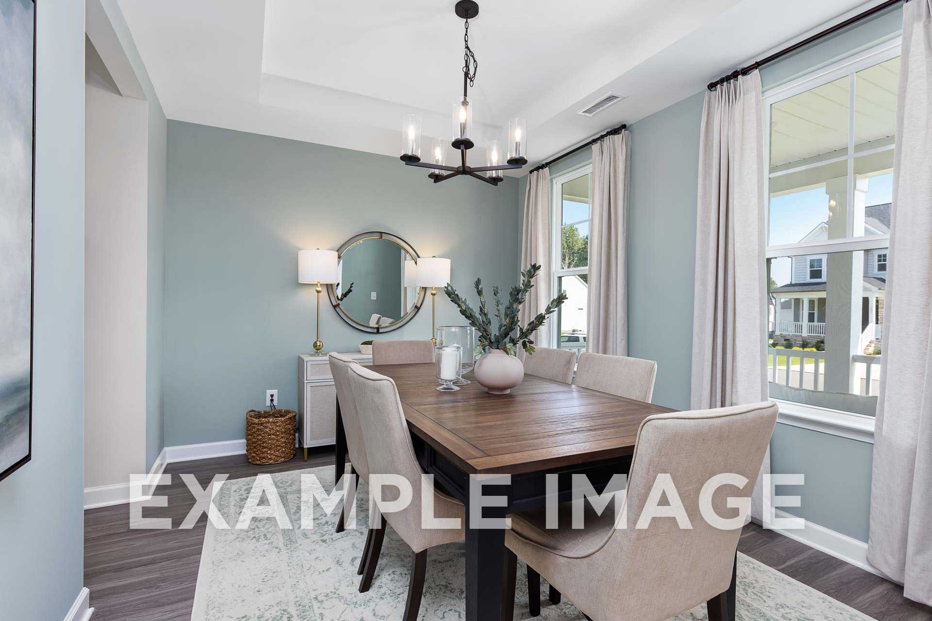 Spacious dining room in The Willow F Davidson Homes with wooden table, beige chairs, chandelier, round mirror, and large window