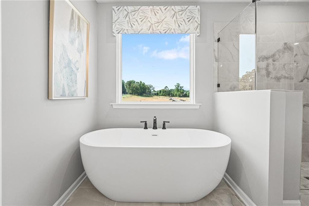 Modern freestanding soaking tub in master bathroom of The Hickory A floor plan at Wehunt Meadows in Hoschton, Georgia.