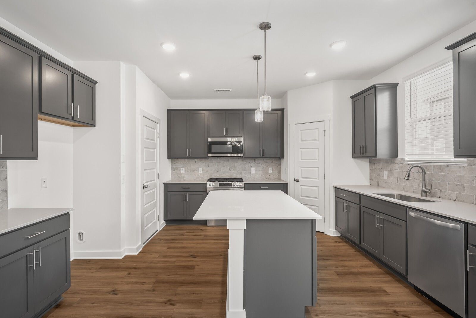 Modern kitchen with gray shaker cabinets, white quartz island, stainless appliances, hardwood floors in The Gordon C, White House, TN