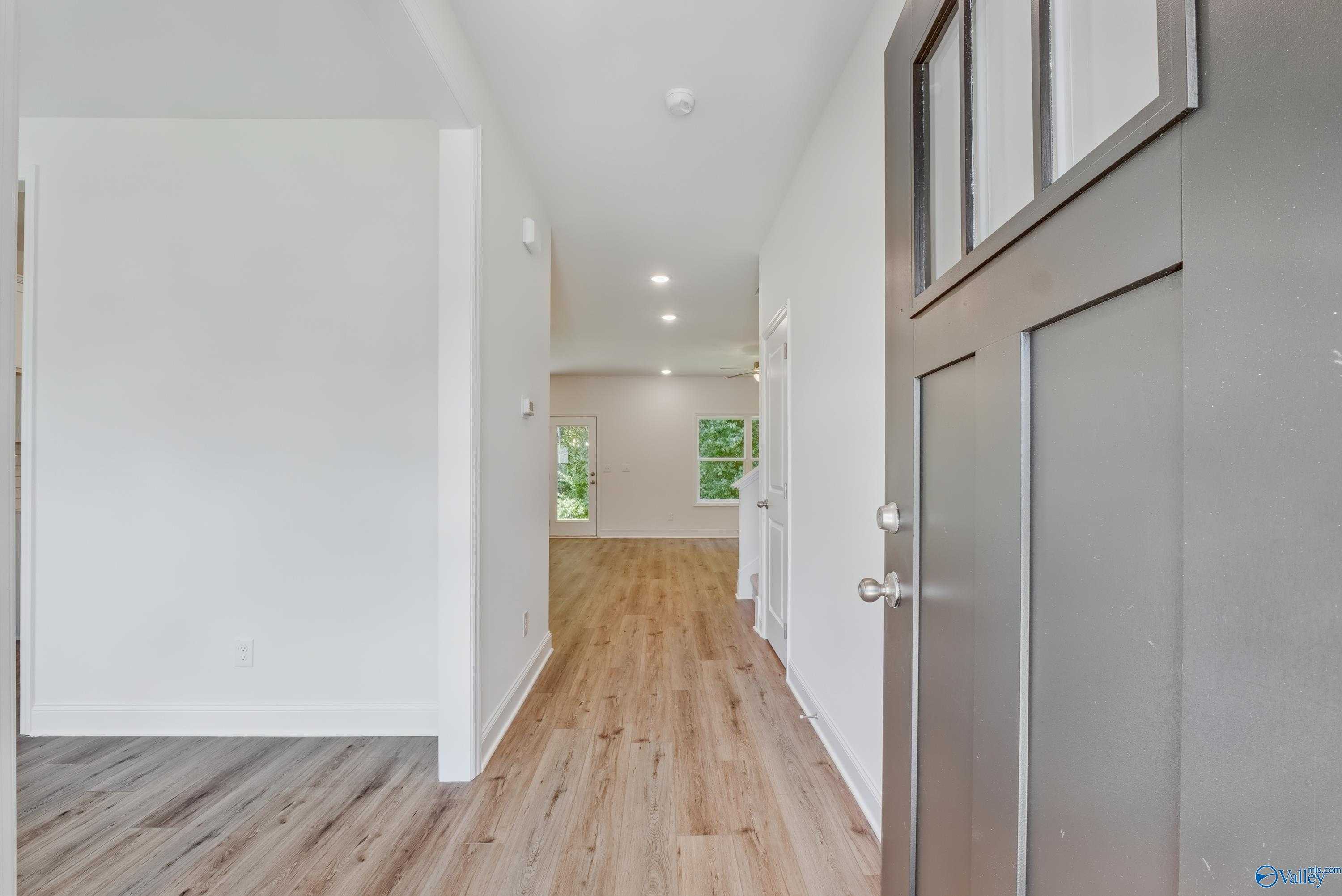 Bright entry hallway with hardwood floors, white walls, and glass-paneled front door in The Shelby A floor plan, Arab, Alabama