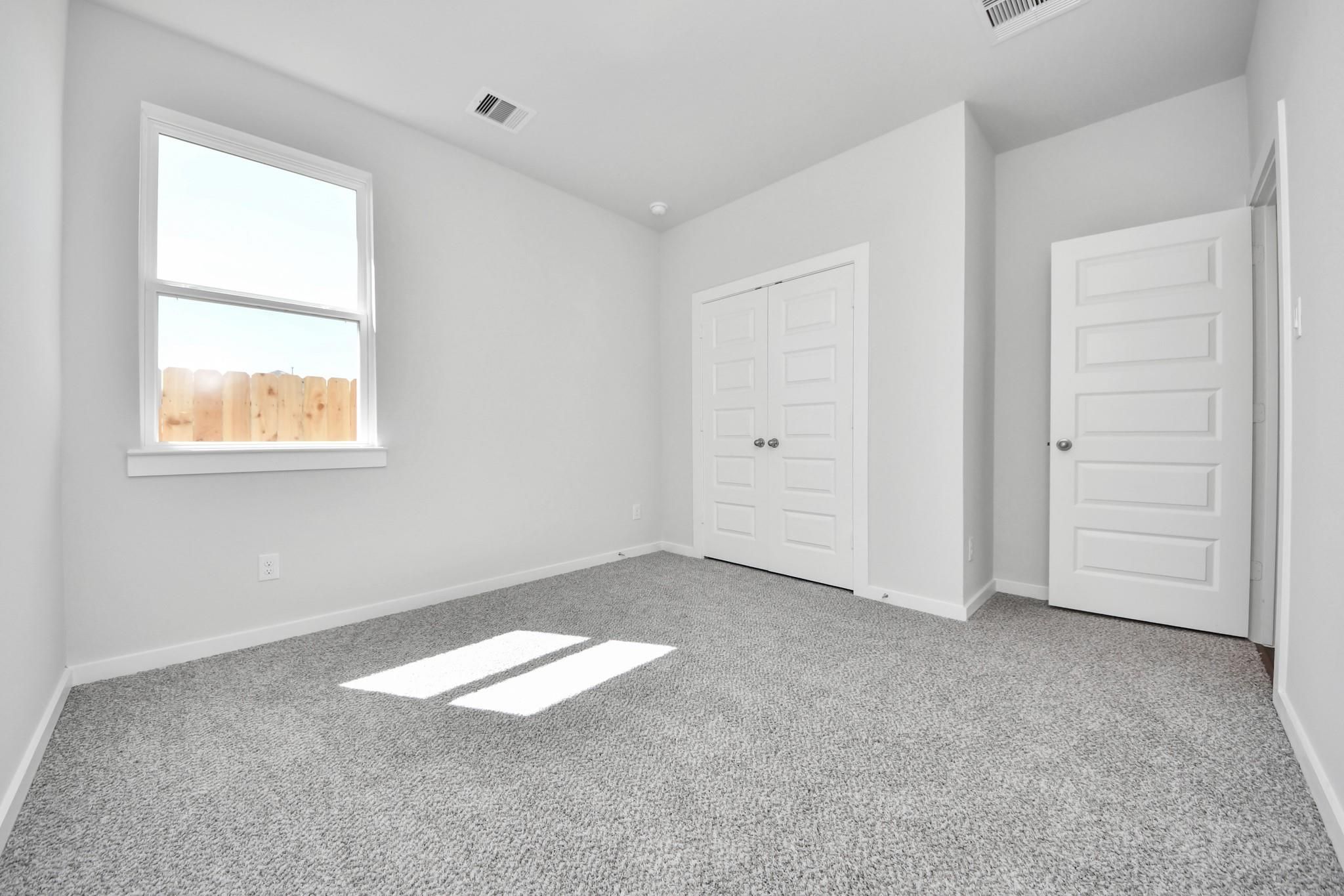 Bright secondary bedroom with carpet and closet in The Riviera A floor plan at Emberly in Beasley, Texas.