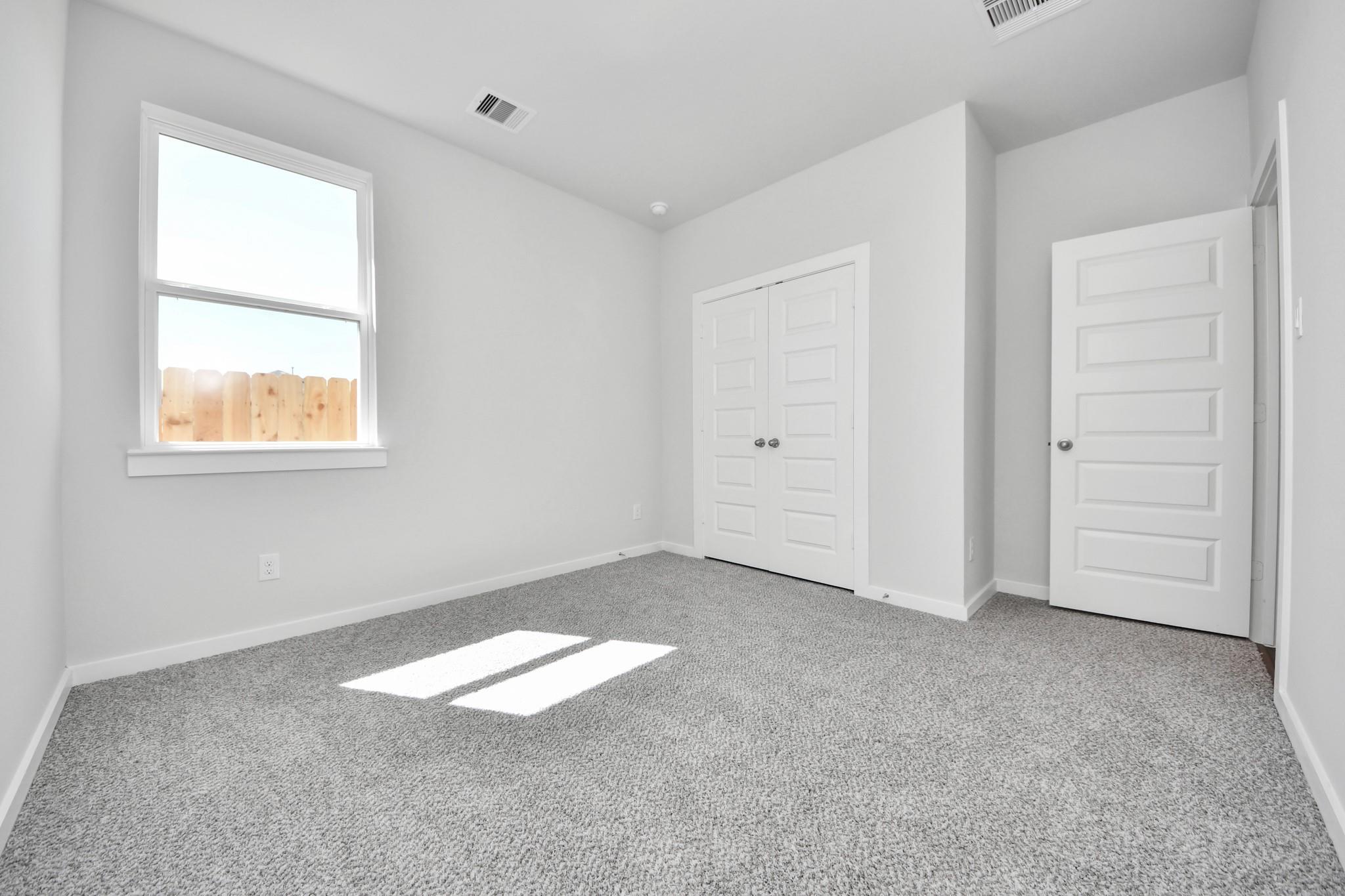 Bright secondary bedroom with carpet and closet in The Riviera A floor plan at Emberly in Beasley, Texas.