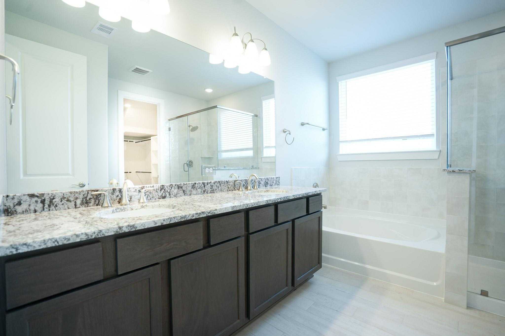Elegant master bath with double granite vanity, dark cabinets, freestanding tub, glass shower in Davidson Homes The Edward C, Texas City