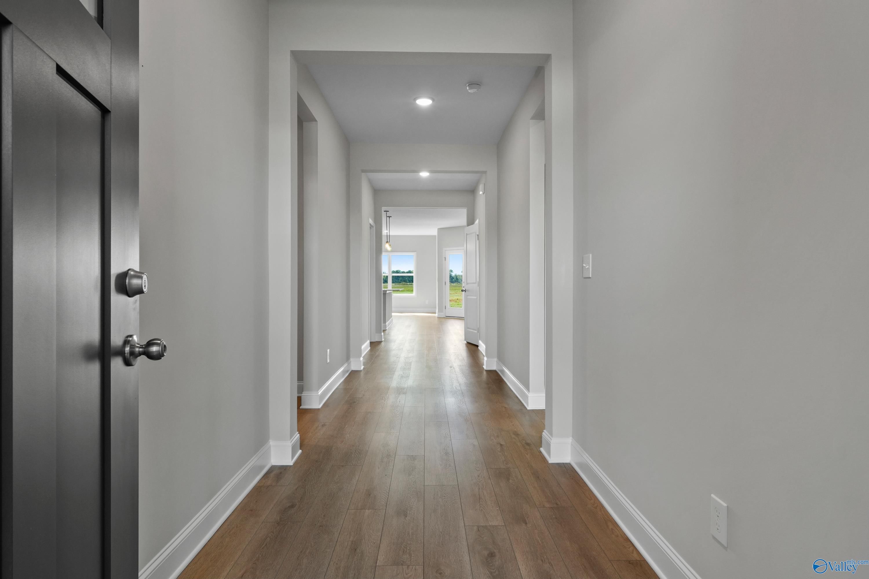 Elegant hallway with hardwood floors, arched openings, and natural light in The Everett 4-bedroom home by Davidson Homes, Hazel Green, Alabama