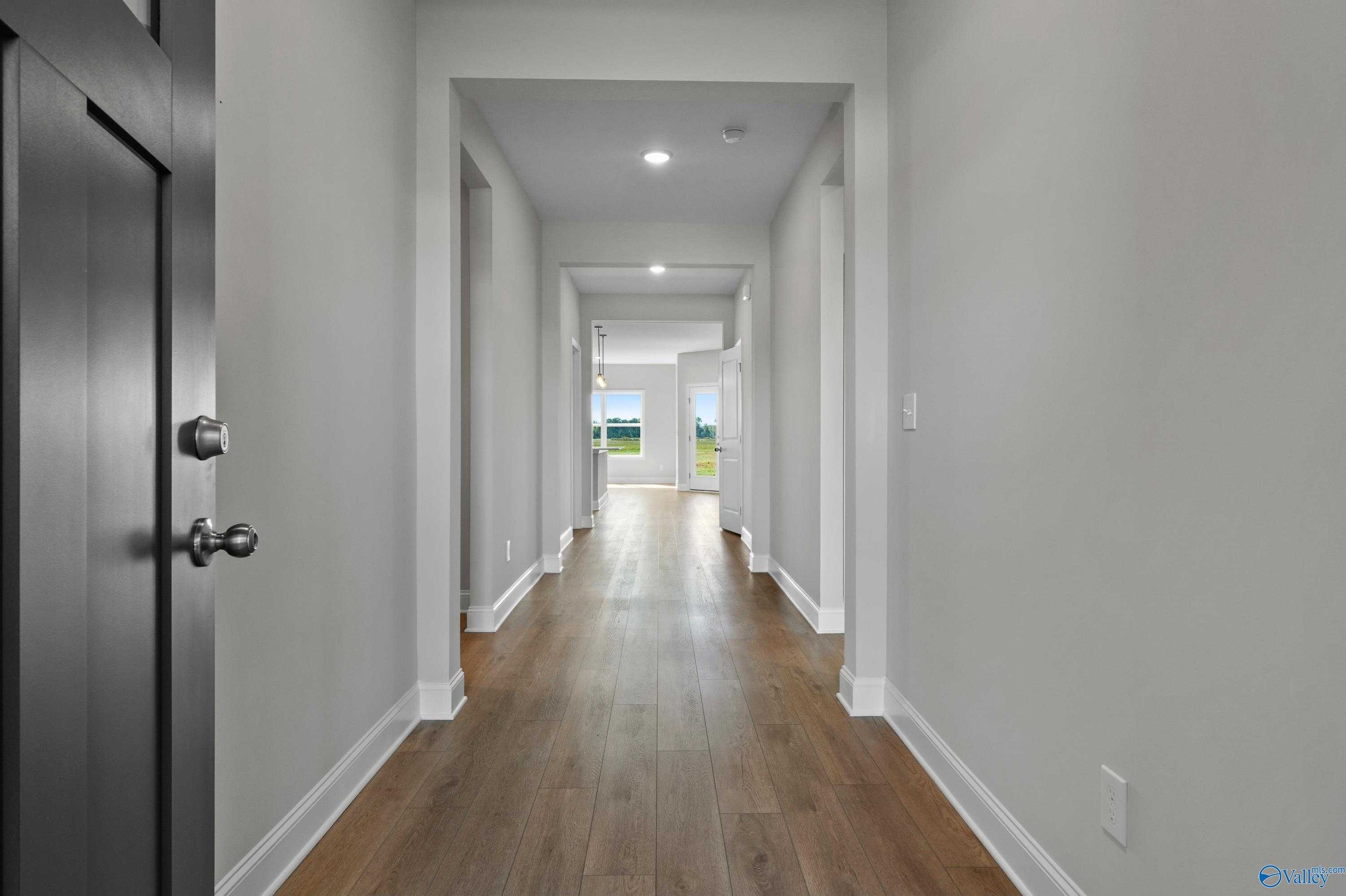 Elegant hallway with hardwood floors, arched openings, and natural light in The Everett 4-bedroom home by Davidson Homes, Hazel Green, Alabama