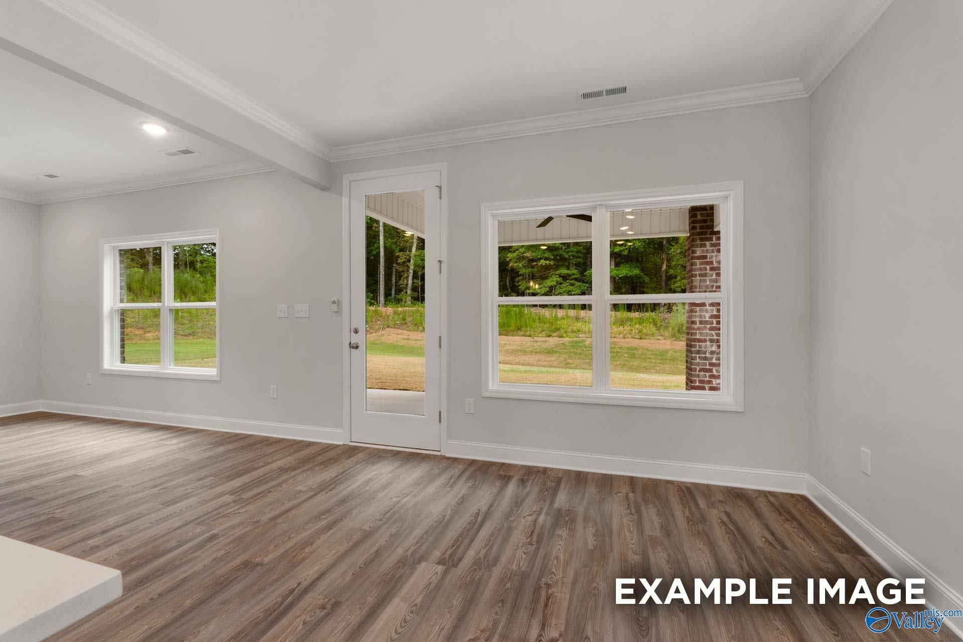 Bright living room with gray walls, hardwood floors, large windows and glass door to wooded backyard in The Shelby C, Arab, Alabama