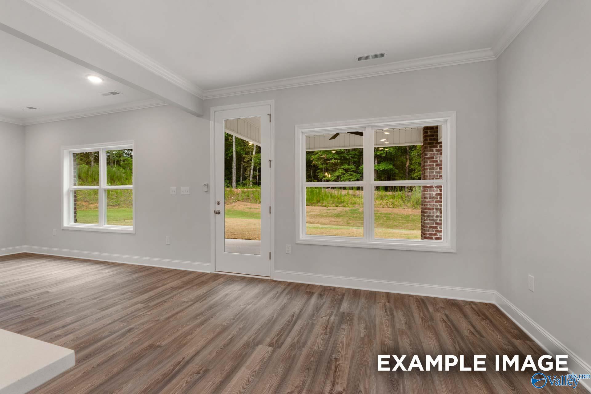 Bright living room with gray walls, hardwood floors, large windows and glass door to wooded backyard in The Shelby C, Arab, Alabama