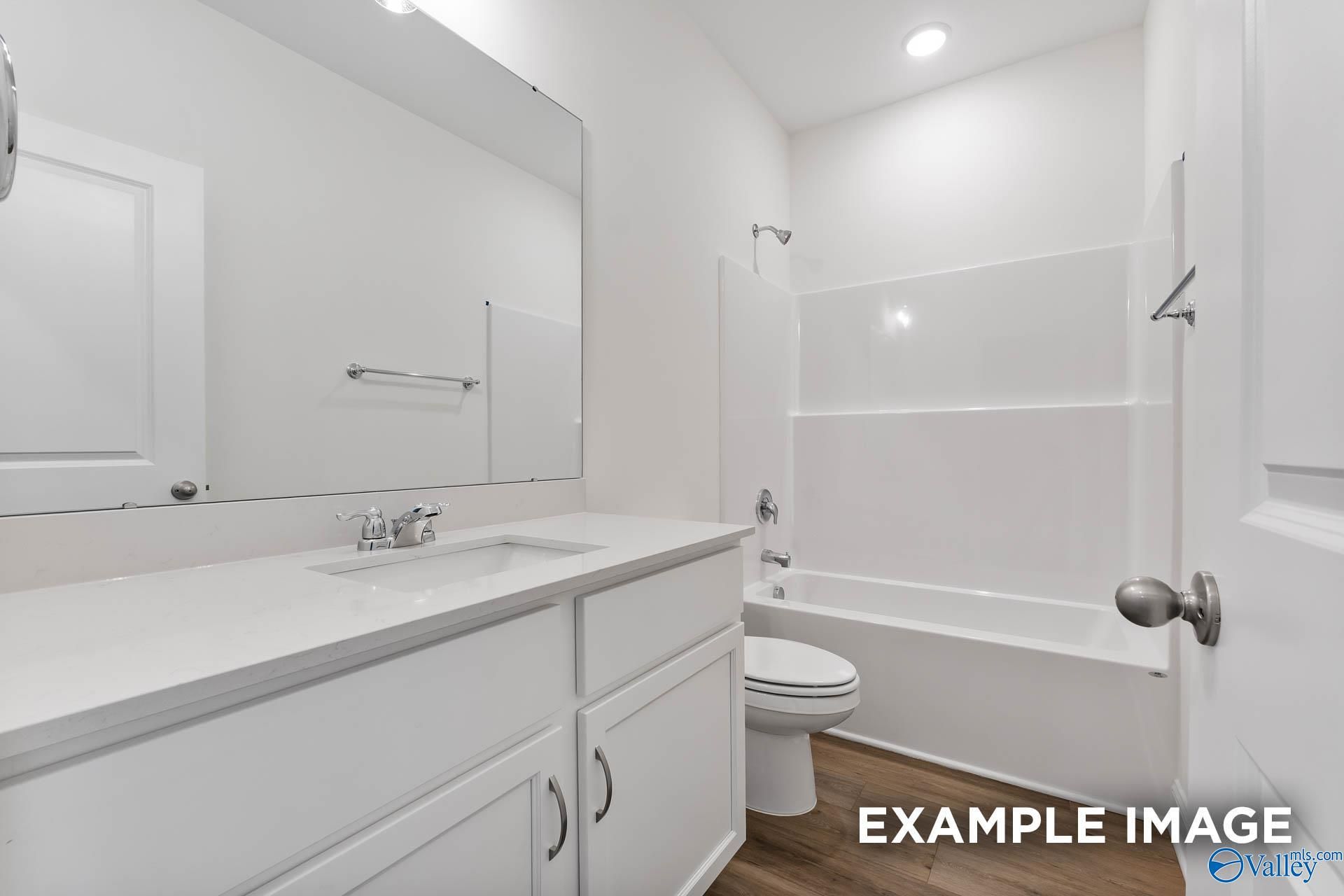 Bright bathroom with double vanity, soaking tub-shower combo, and wood floors in Davidson Homes The Daphne V, Athens, Alabama