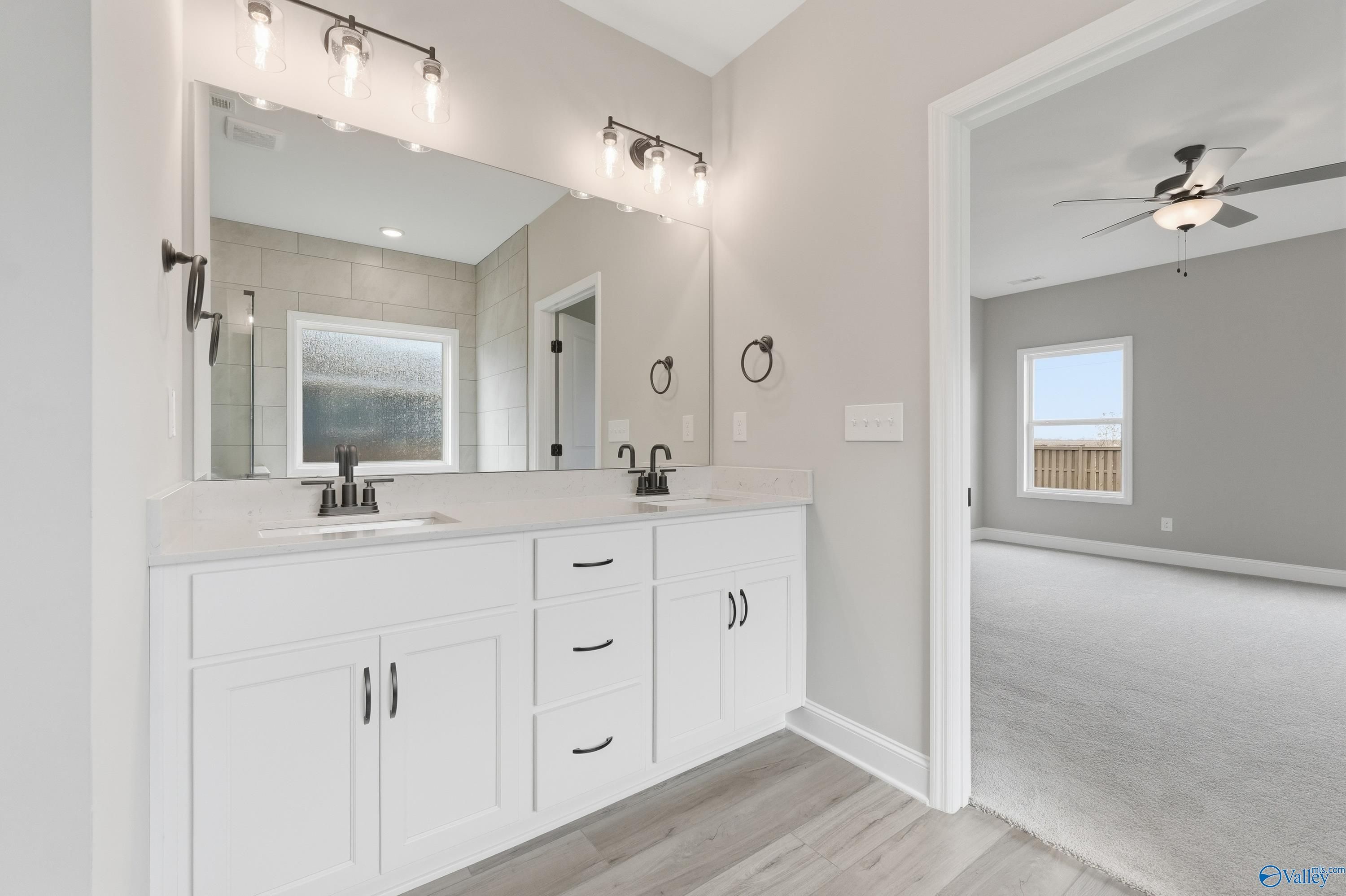 Modern master bathroom featuring double white vanity, mirrors, and neutral tones in Davidson Homes The Rockford C, Athens, Alabama