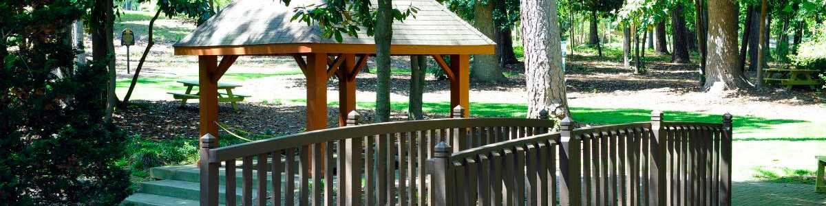 Serene wooden gazebo and footbridge amid lush trees in Willow Spring new home community