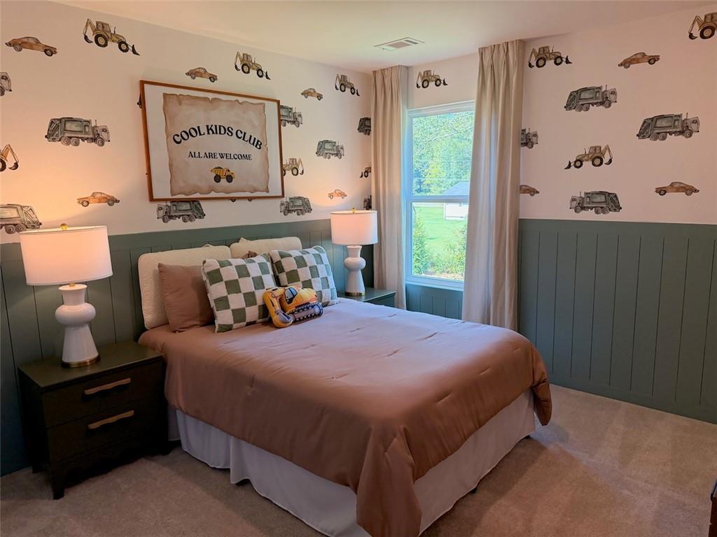 Playful kids bedroom with vintage truck wallpaper, green wainscoting, and cozy queen bed in Davidson Homes Pinecrest J, Cartersville.