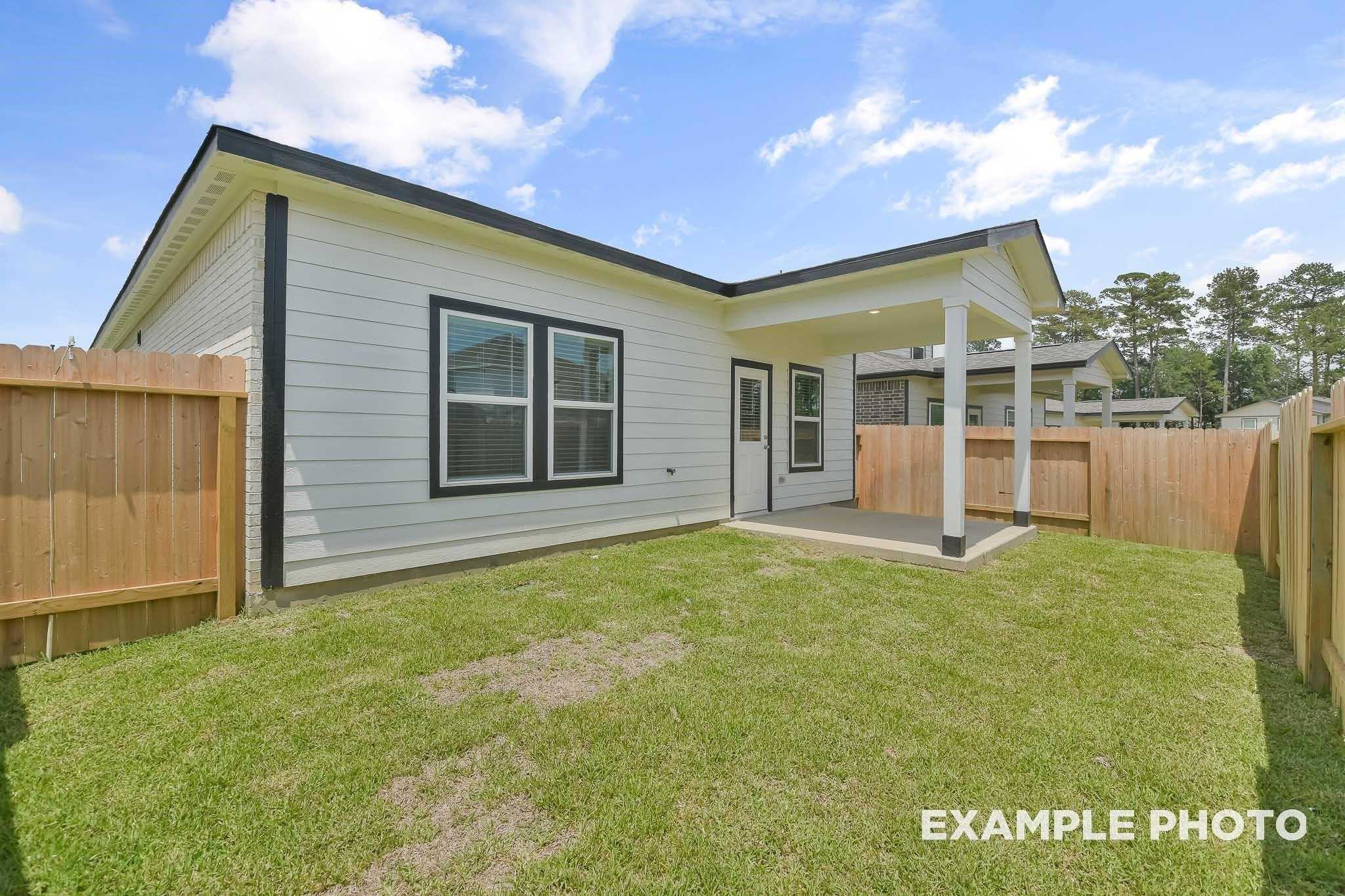 Modern single-story home exterior with black-trimmed windows, covered patio, wooden fence, and lush green yard in Conroe, Texas