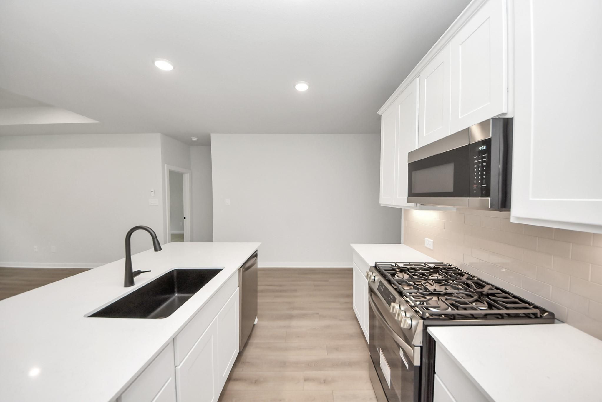 Modern kitchen with white cabinets, quartz island, and stainless appliances in The Daphne F home, Sundance Cove, Crosby.