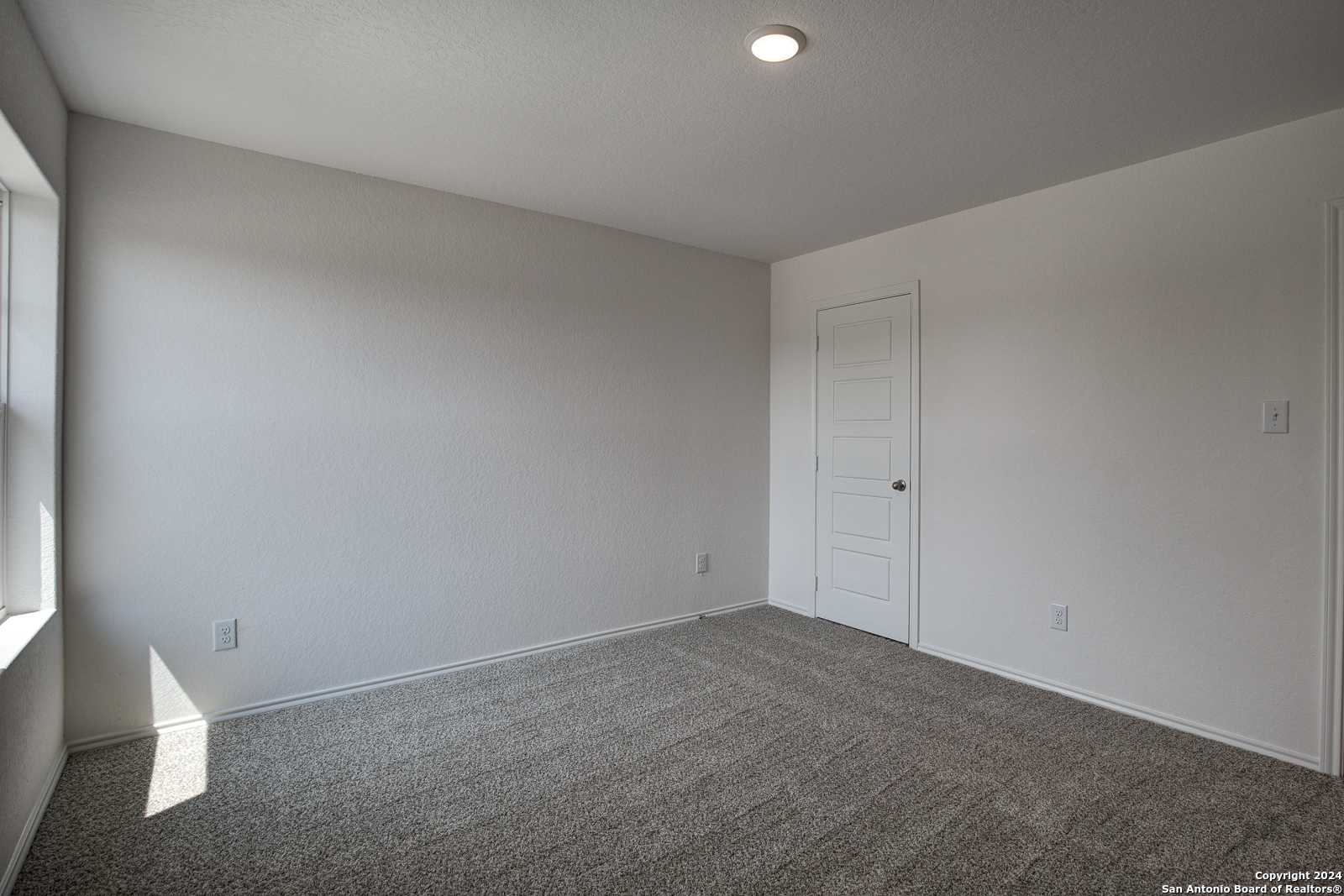 Bright secondary bedroom with beige carpet, large window, and white walls in Davidson Homes The Douglas D, Seguin, Texas