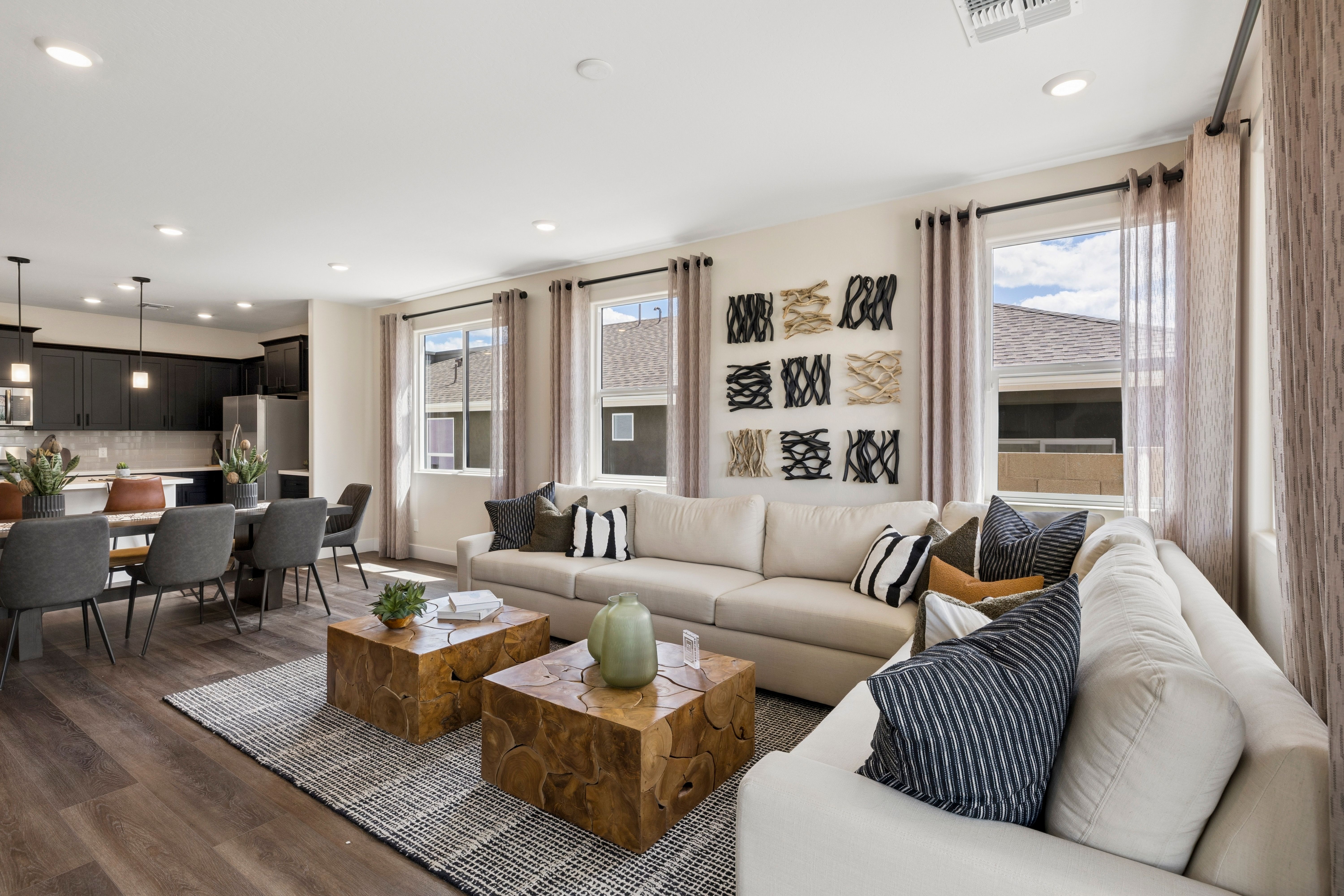 Open-concept living room at South Ranch Western Collection in Prescott AZ with beige sofa, wooden tables, hardwood floors, and large windows