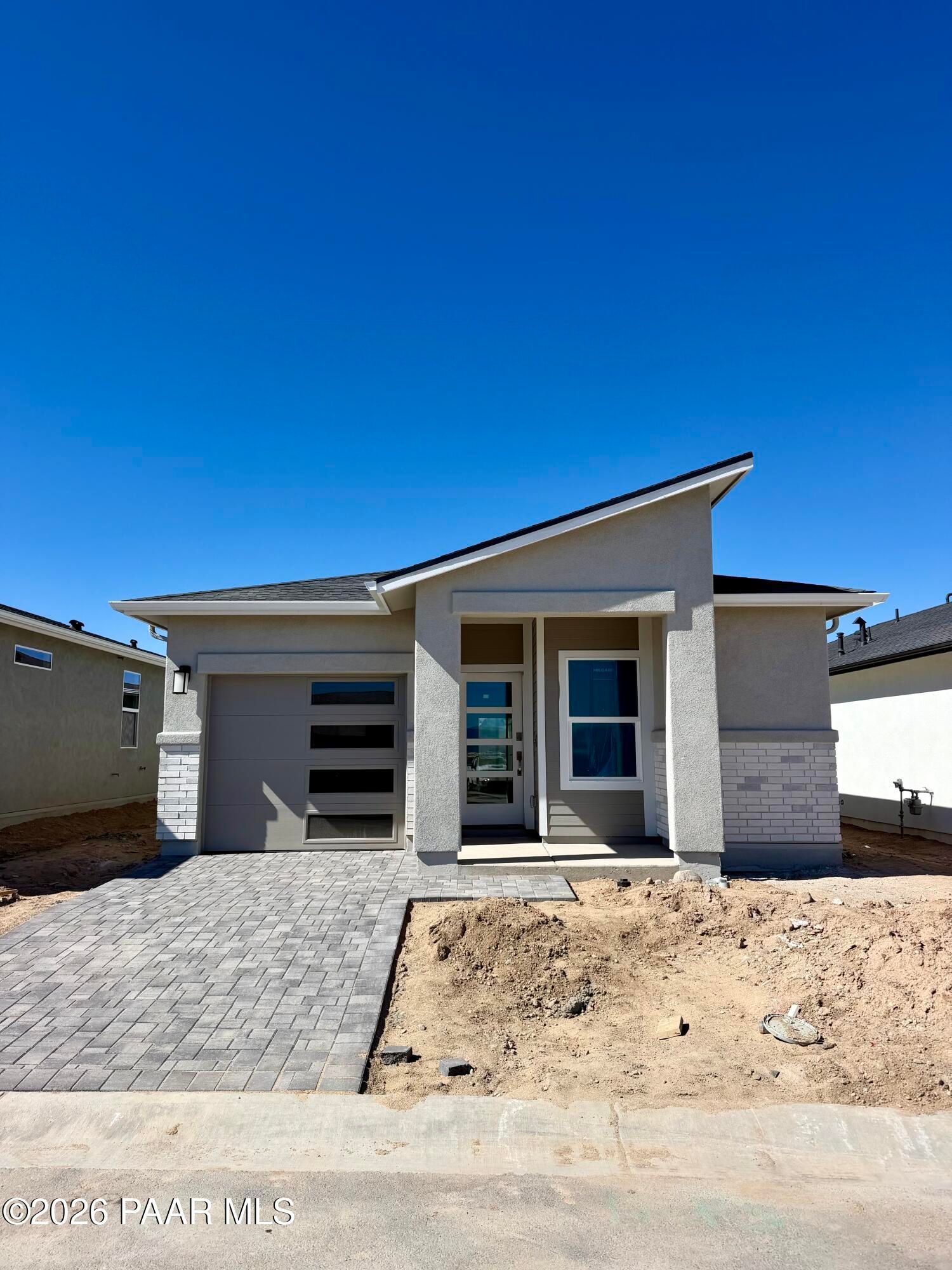 Modern stucco home exterior with angled roofline, brick accents, and paver driveway at South Ranch Southern Collection, Prescott, Arizona.