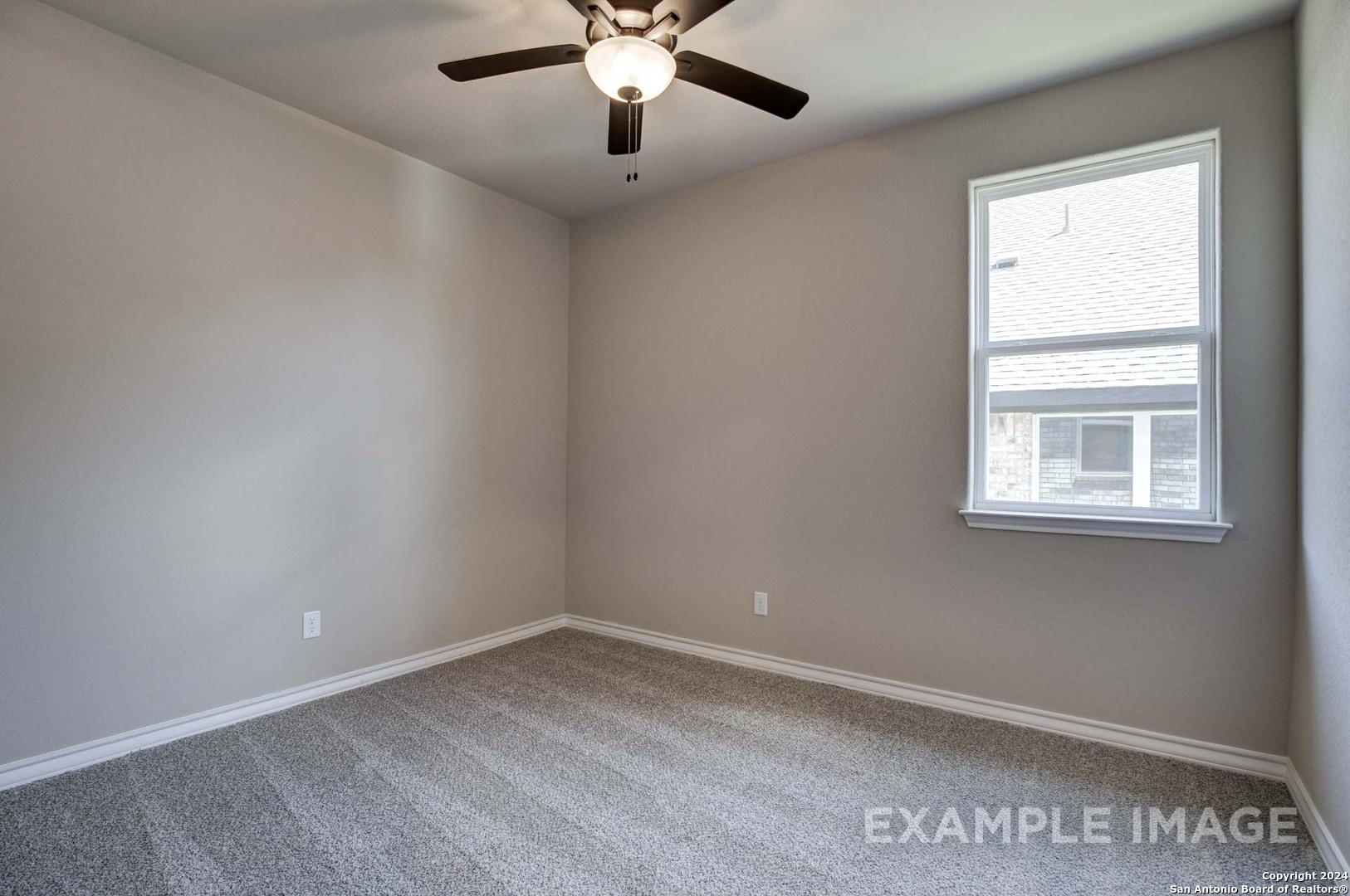 Bright secondary bedroom featuring beige walls, ceiling fan light, large window, and neutral carpet in Davidson Homes The Rockford G, Ladera, San Antonio