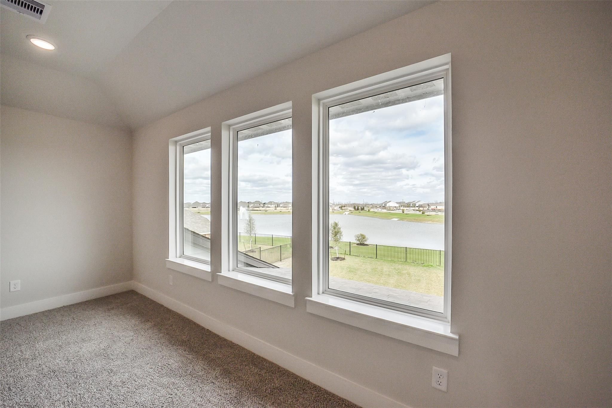 Bright room with three large windows overlooking lake and green landscape in Davidson Homes The Philip B, Rosharon, Texas