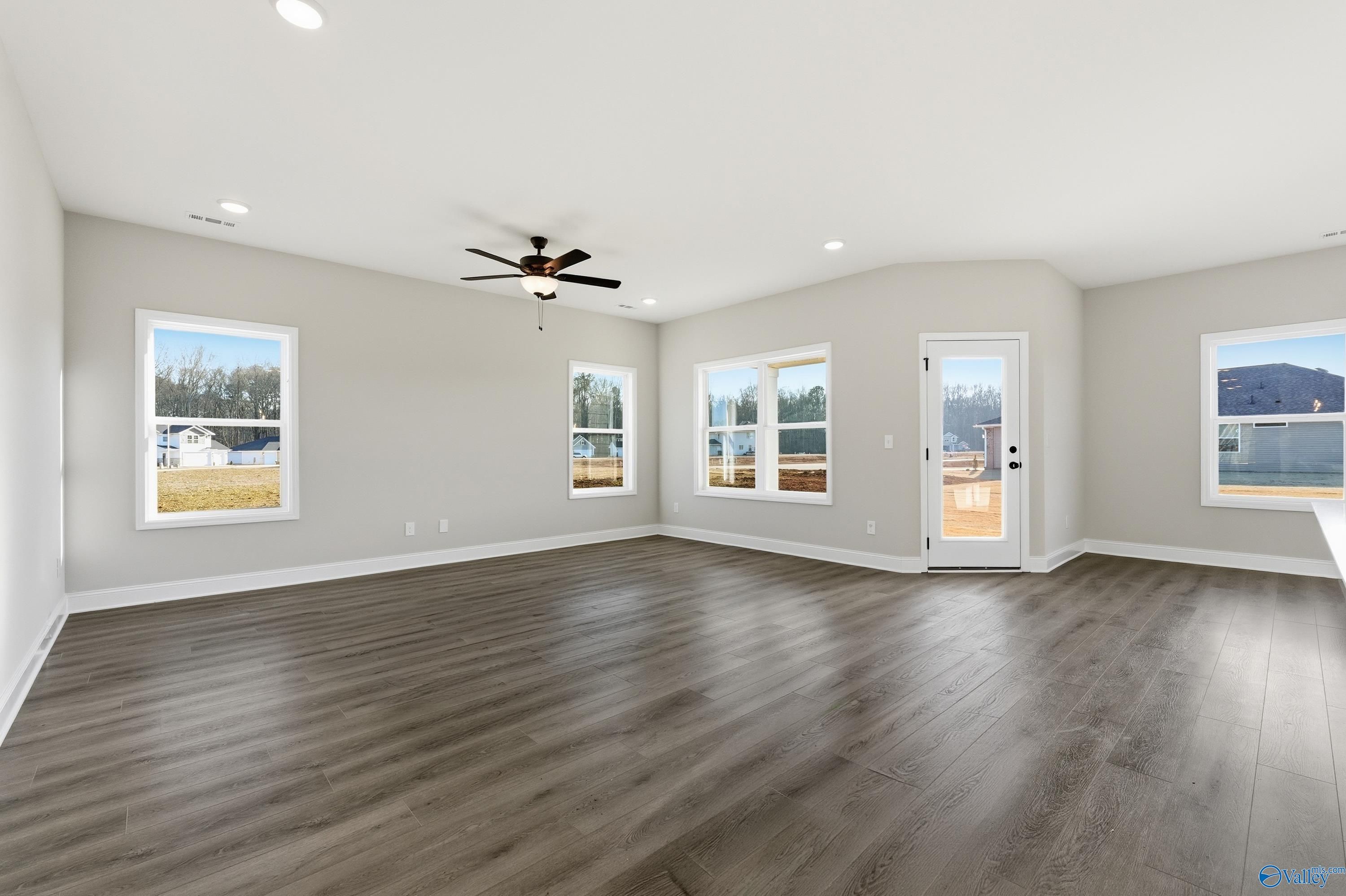 Spacious living room with ceiling fan, large windows, and glass door to deck in 3-bedroom Davidson Homes Franklin E, Hazel Green AL