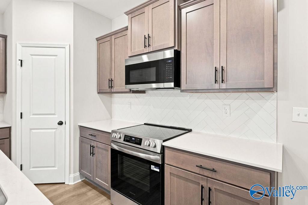 Modern kitchen with wood cabinets, white countertops, and herringbone backsplash in The Camilla C home, Hartselle, AL.