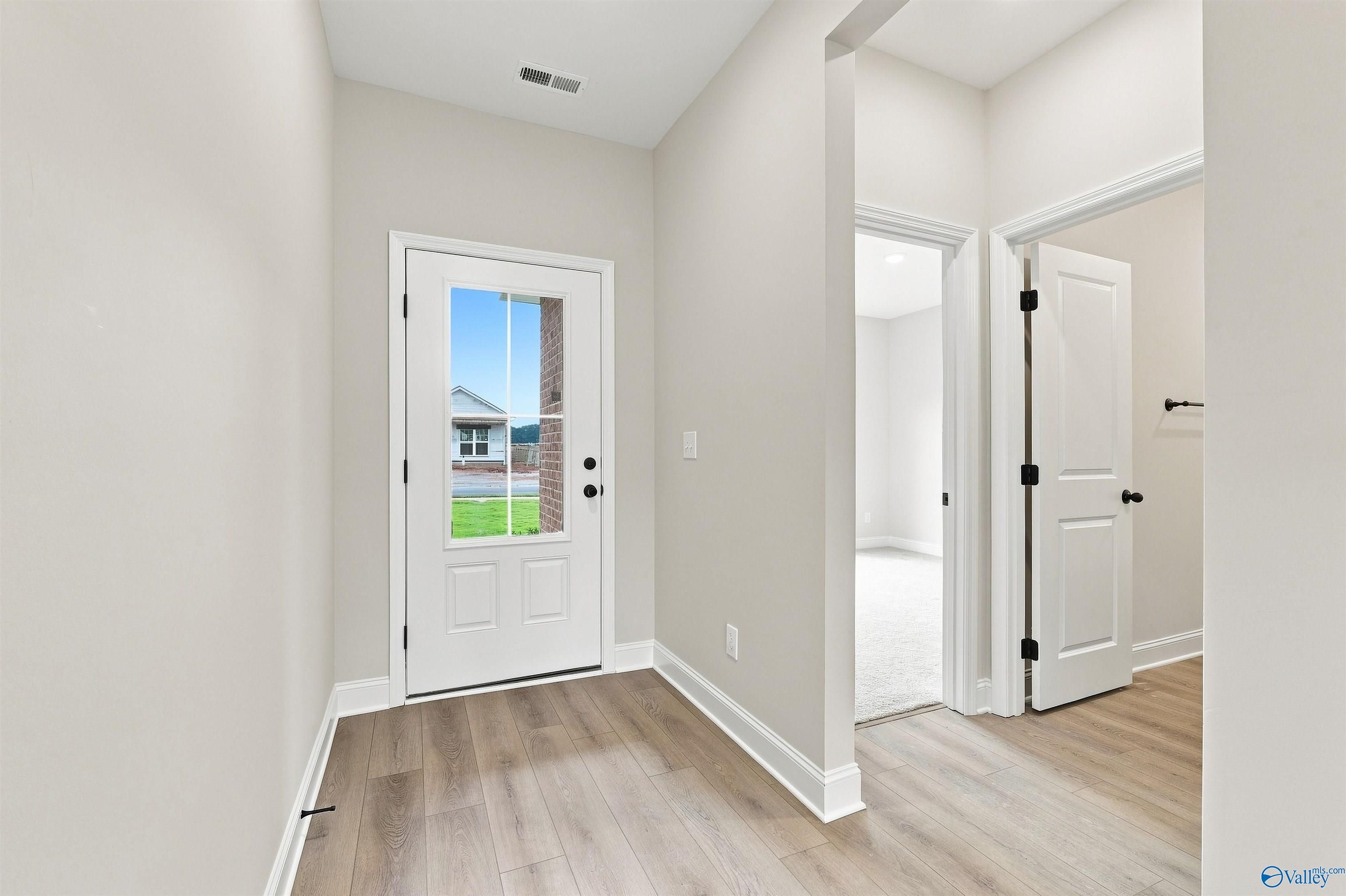 Bright foyer with glass-paneled front door and luxury vinyl plank flooring in Davidson Homes' Franklin C plan, The Meadows, Athens, AL