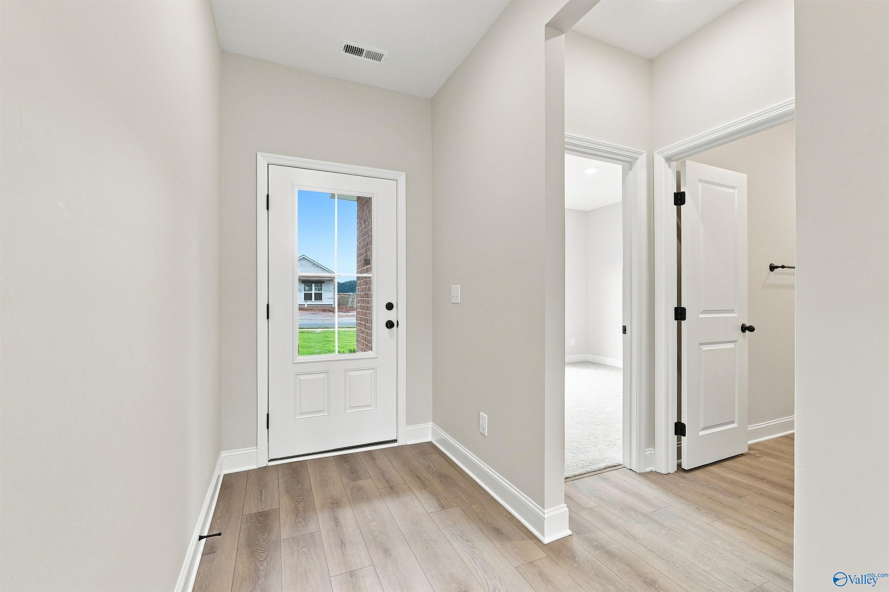 Bright foyer with glass-paneled front door and luxury vinyl plank flooring in Davidson Homes' Franklin C plan, The Meadows, Athens, AL
