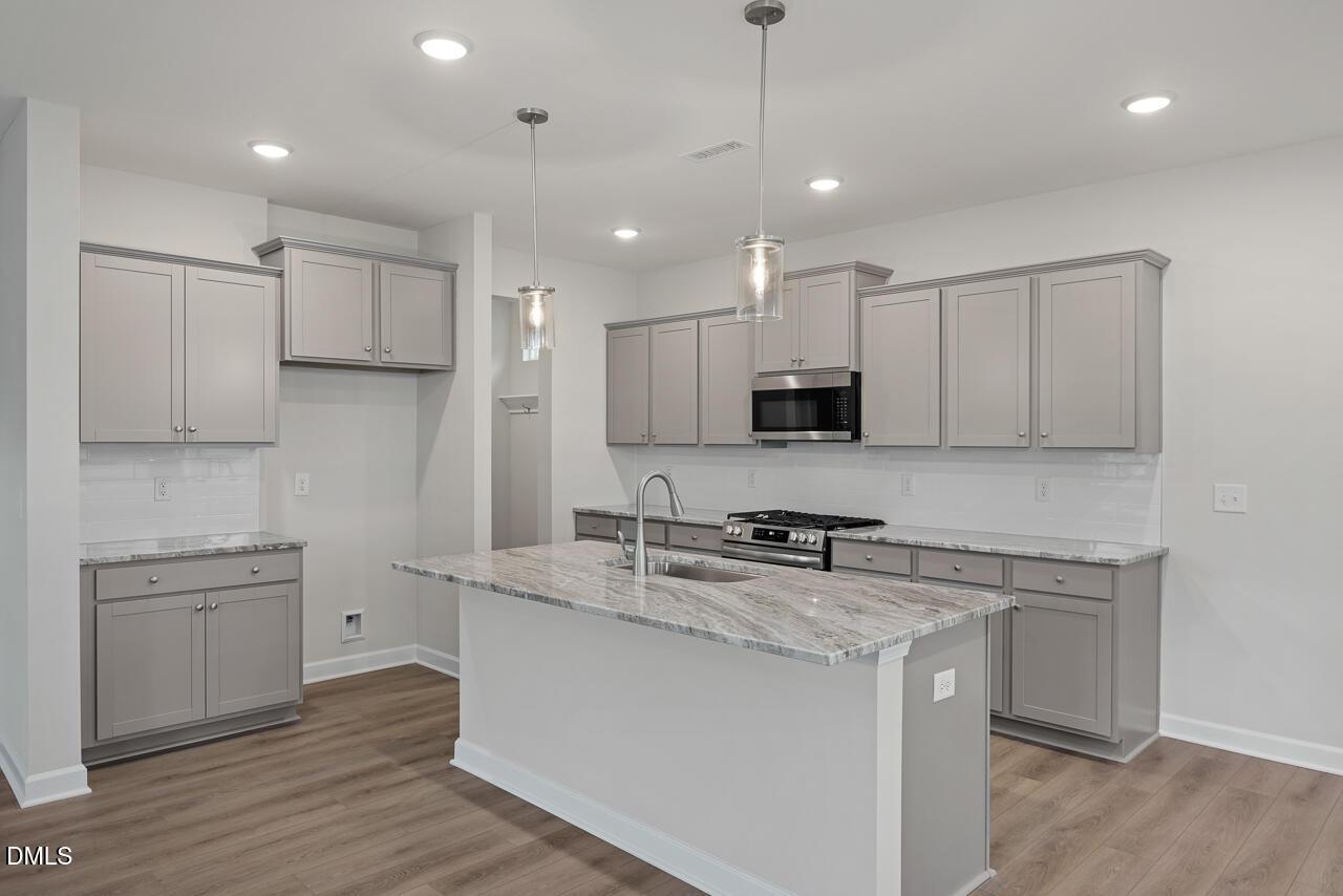 Modern gray shaker kitchen with granite island sink, stainless appliances, subway tile in The Gavin B, Lillington, NC