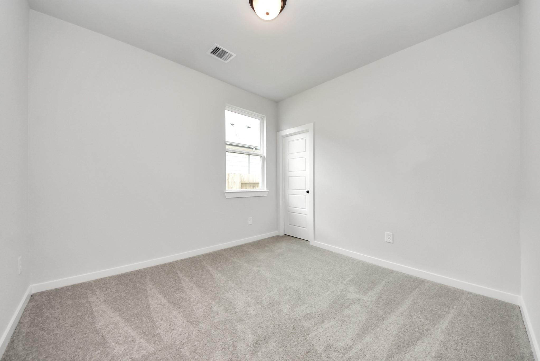 Bright bedroom with neutral walls and carpet in The Daphne F floor plan at Sundance Cove, Crosby, Texas.
