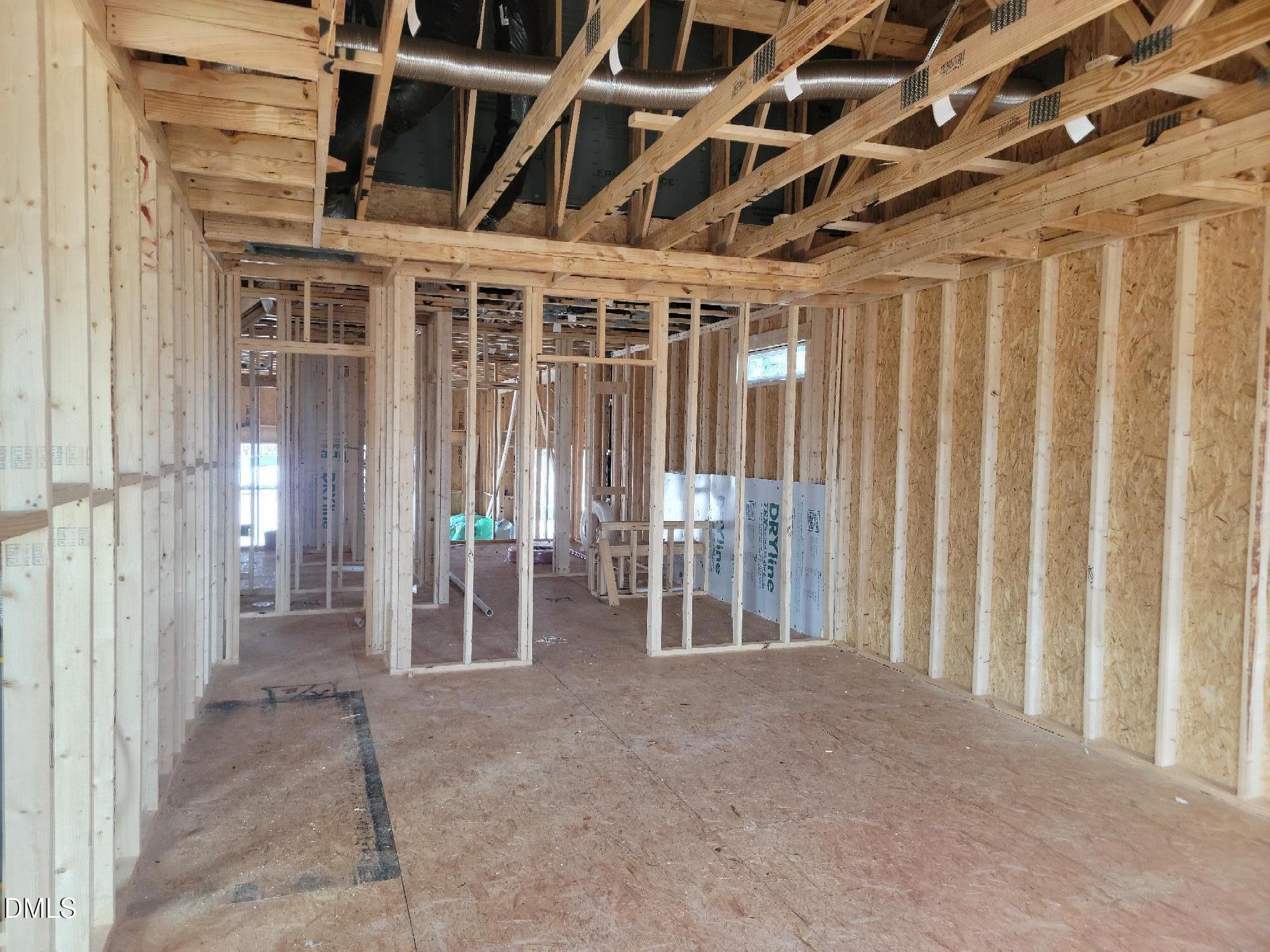 Framed open interior with wooden studs, ceiling joists, and HVAC ducts in The Cypress B II 4-bedroom home, Angier, NC