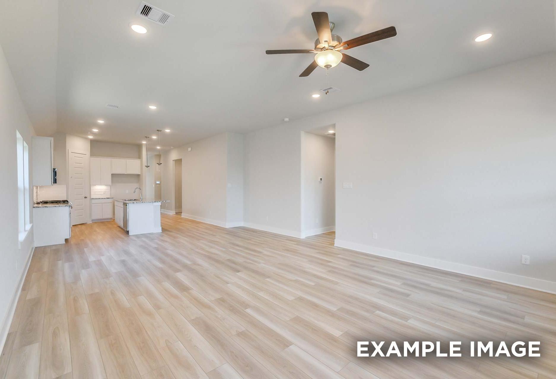 Spacious open-concept kitchen in The Greenfield with white cabinets, central island, ceiling fan, and light hardwood floors