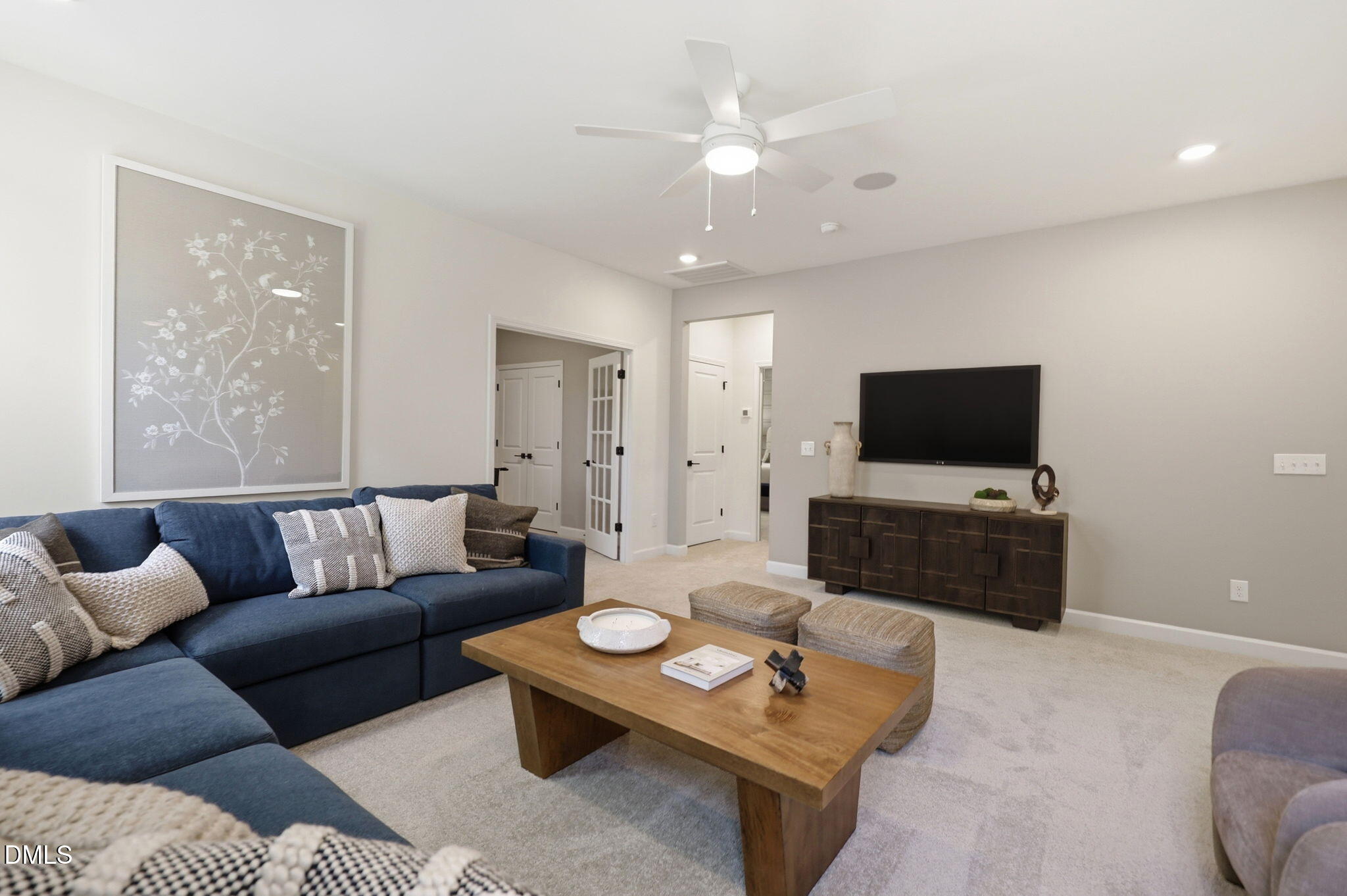 Modern living room with blue sectional, wood coffee table, and flat-screen TV in The Aspen B home at Wendell Ridge.