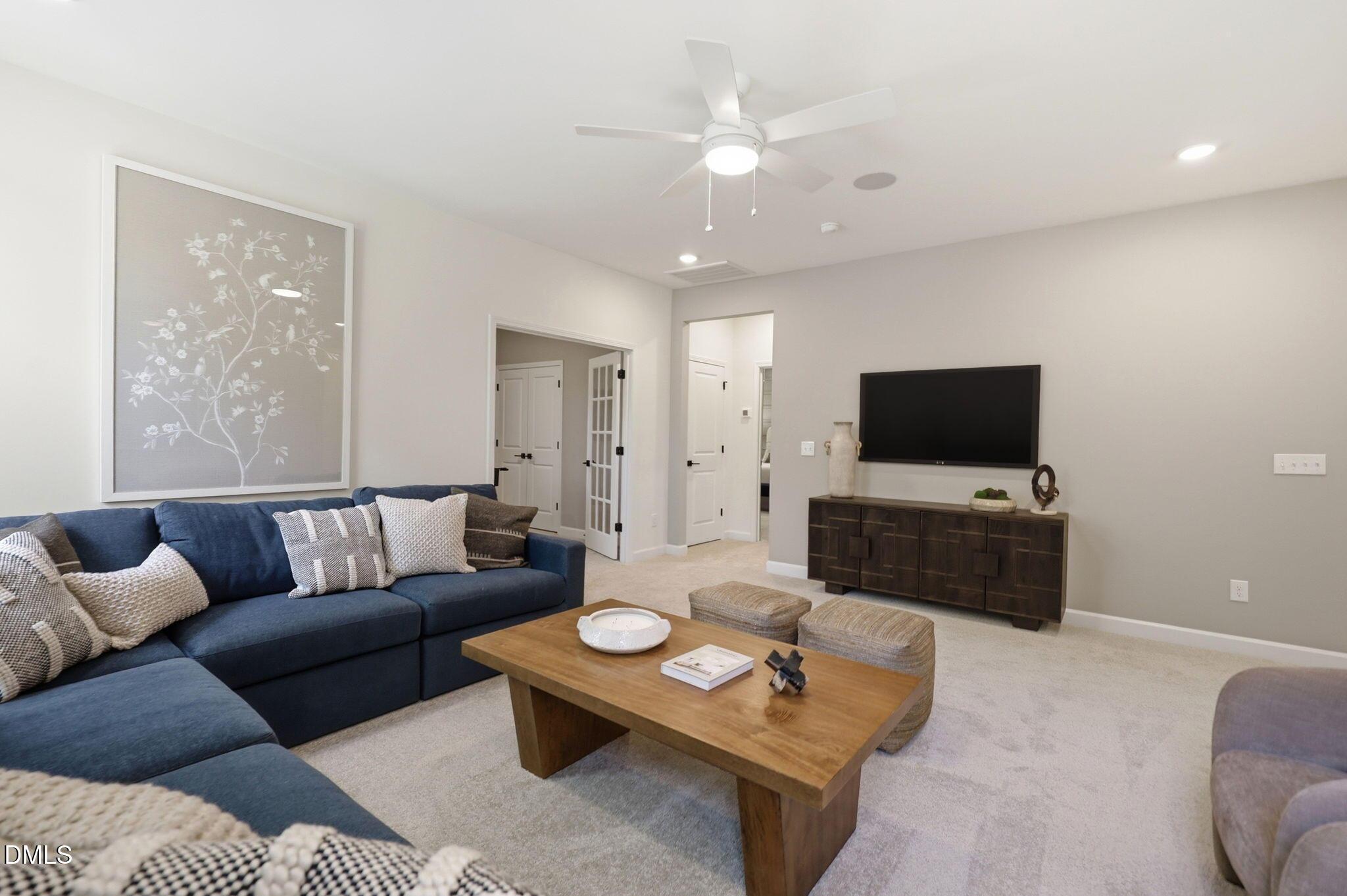 Modern living room with blue sectional, wood coffee table, and flat-screen TV in The Aspen B home at Wendell Ridge.
