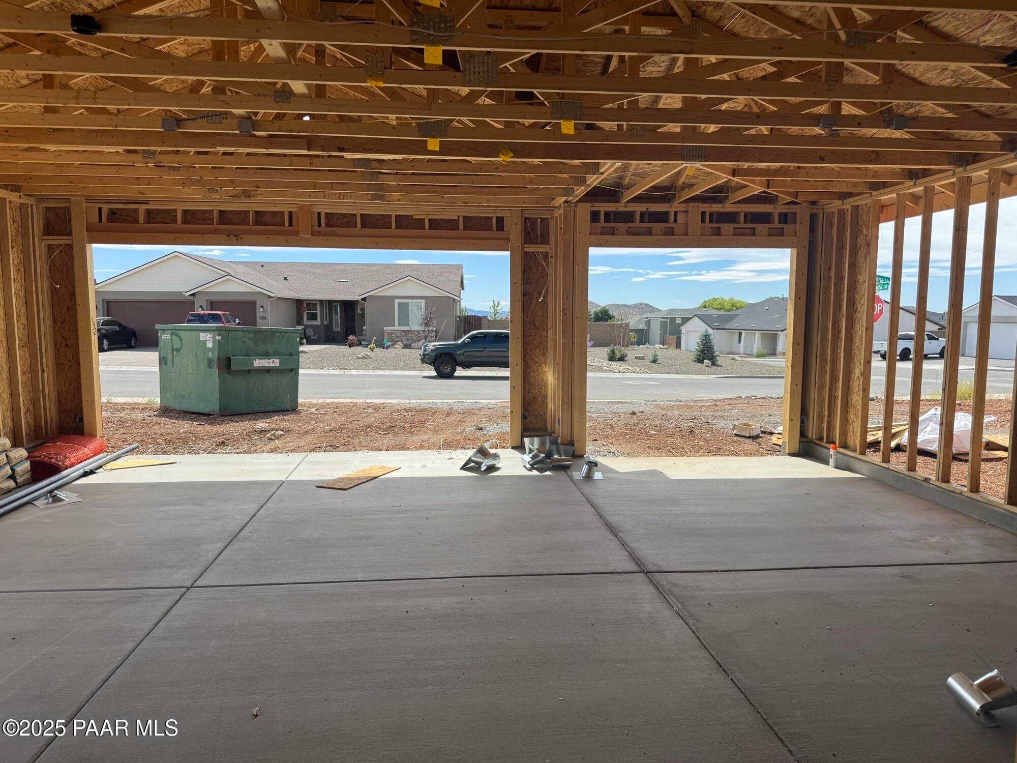 Spacious 3-car garage under construction with open wooden frames and concrete flooring in Evermore Homes The Monarch B, Prescott Valley, Arizona
