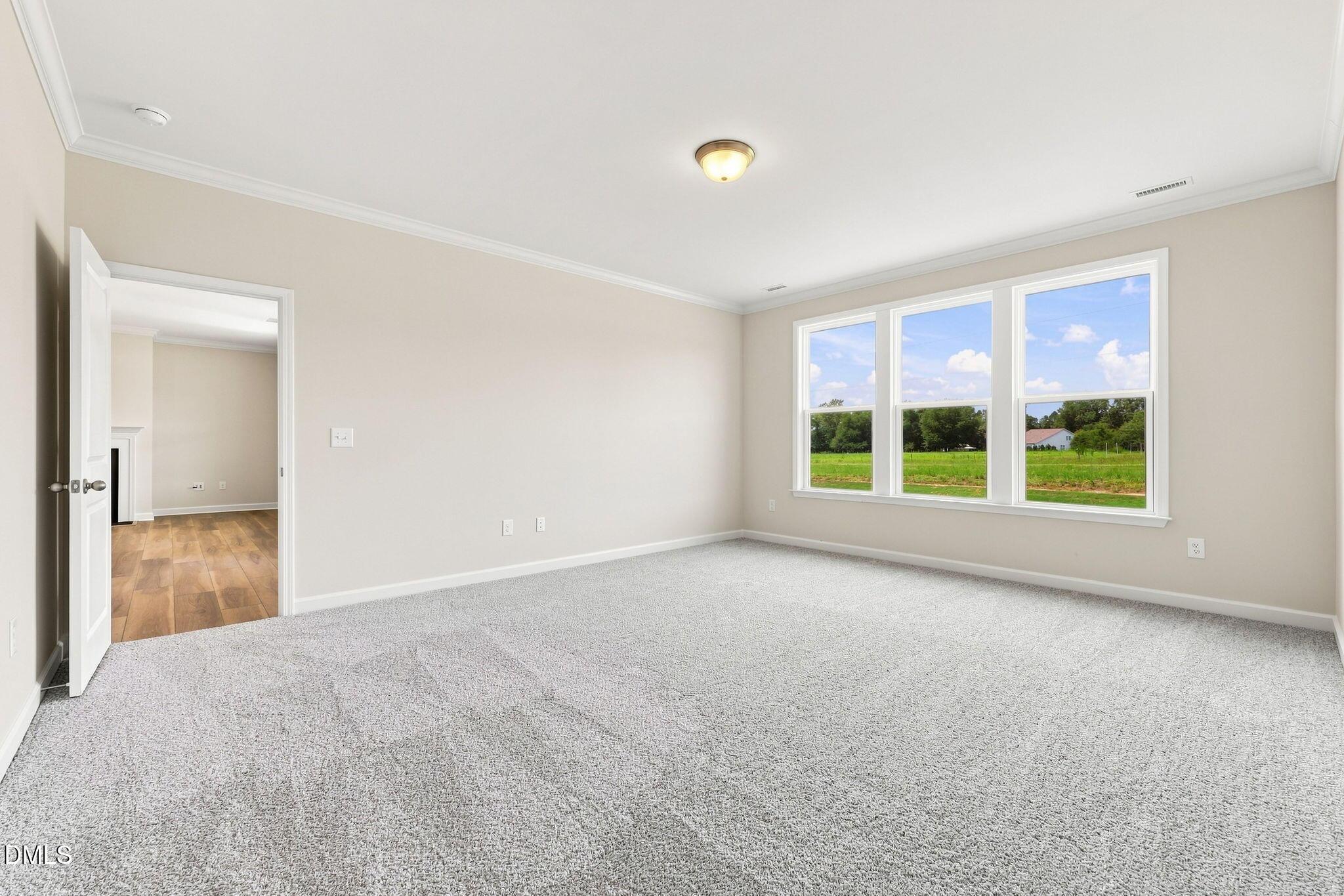 Bright, carpeted bedroom with large windows and country views in The Magnolia B floor plan at Retreat at North Main.