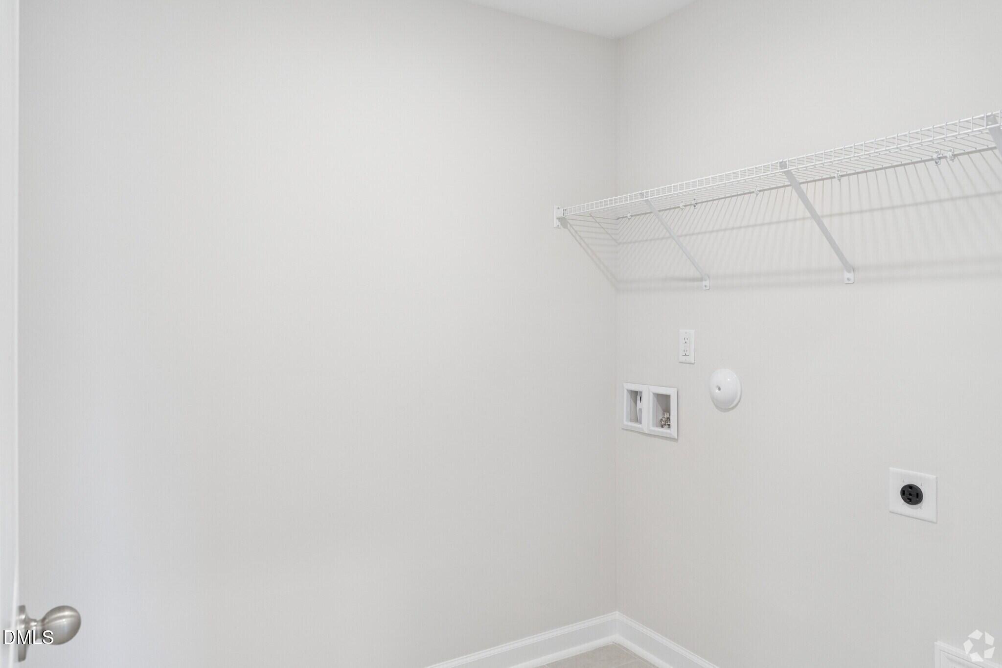 Laundry room with wire shelving and washer hookups in Davidson Homes' The Avery townhome, Forestville Yard, Knightdale NC