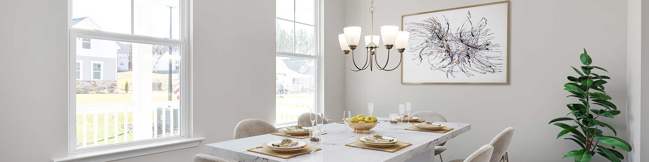 Modern dining room in new Mebane home with white table, beige chairs, chandelier, abstract art, and porch view