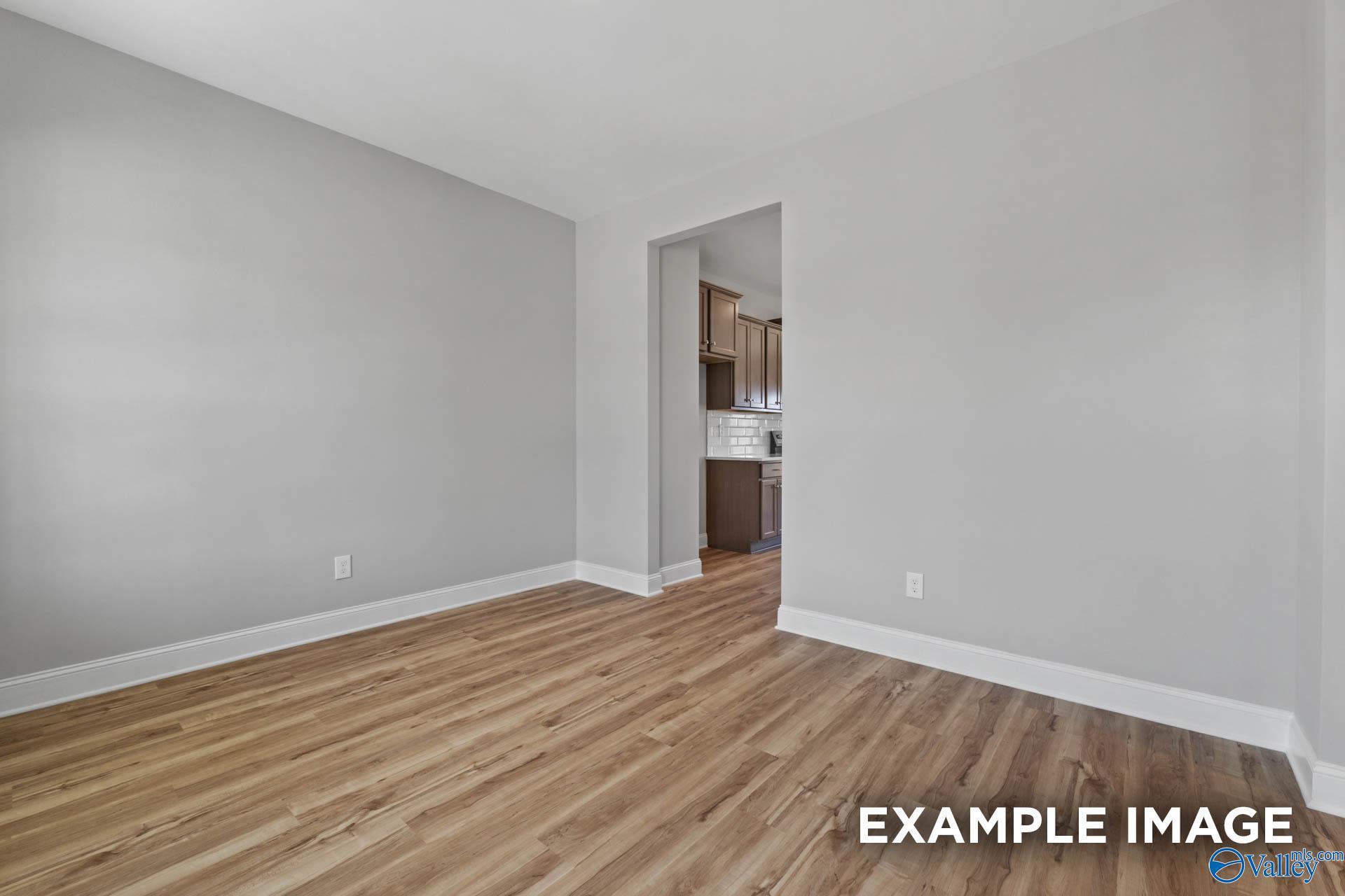 Neutral-toned dining area with wood-style flooring opening to a modern kitchen in The Shelby B at Creek Grove, New Market.