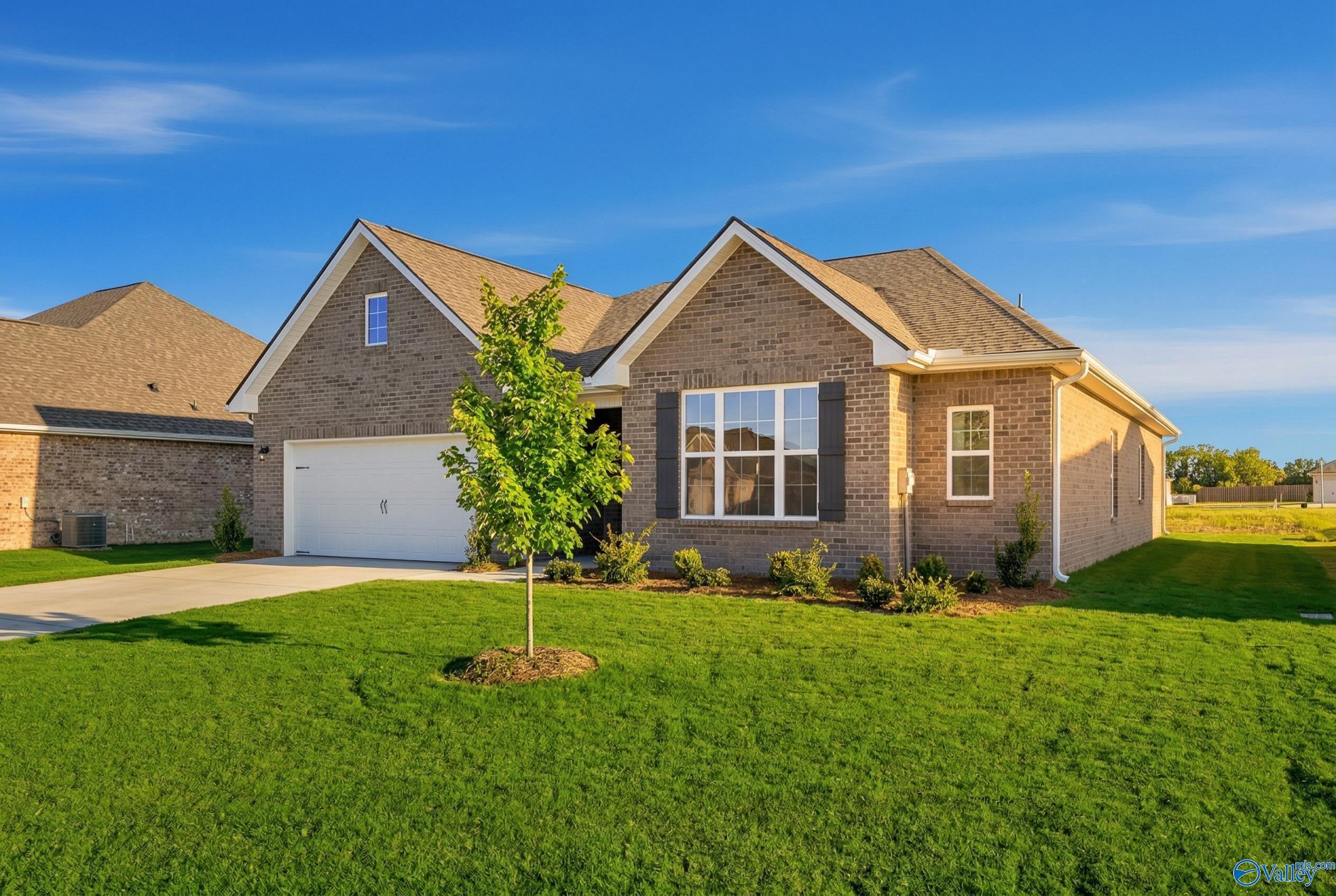 Charming 1-story brick home with gabled roof, 2-car garage, young tree, and green lawn in Pikes Ridge, Meridianville, Alabama - Davidson Homes Montgomery