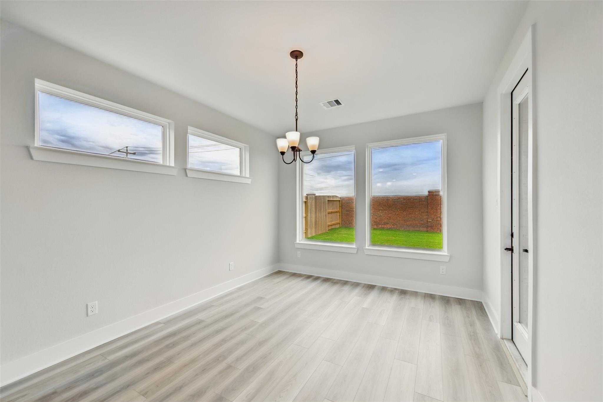 Bright room with chandelier, large windows overlooking grassy backyard in Davidson Homes The Victoria C, Lago Mar, Texas City