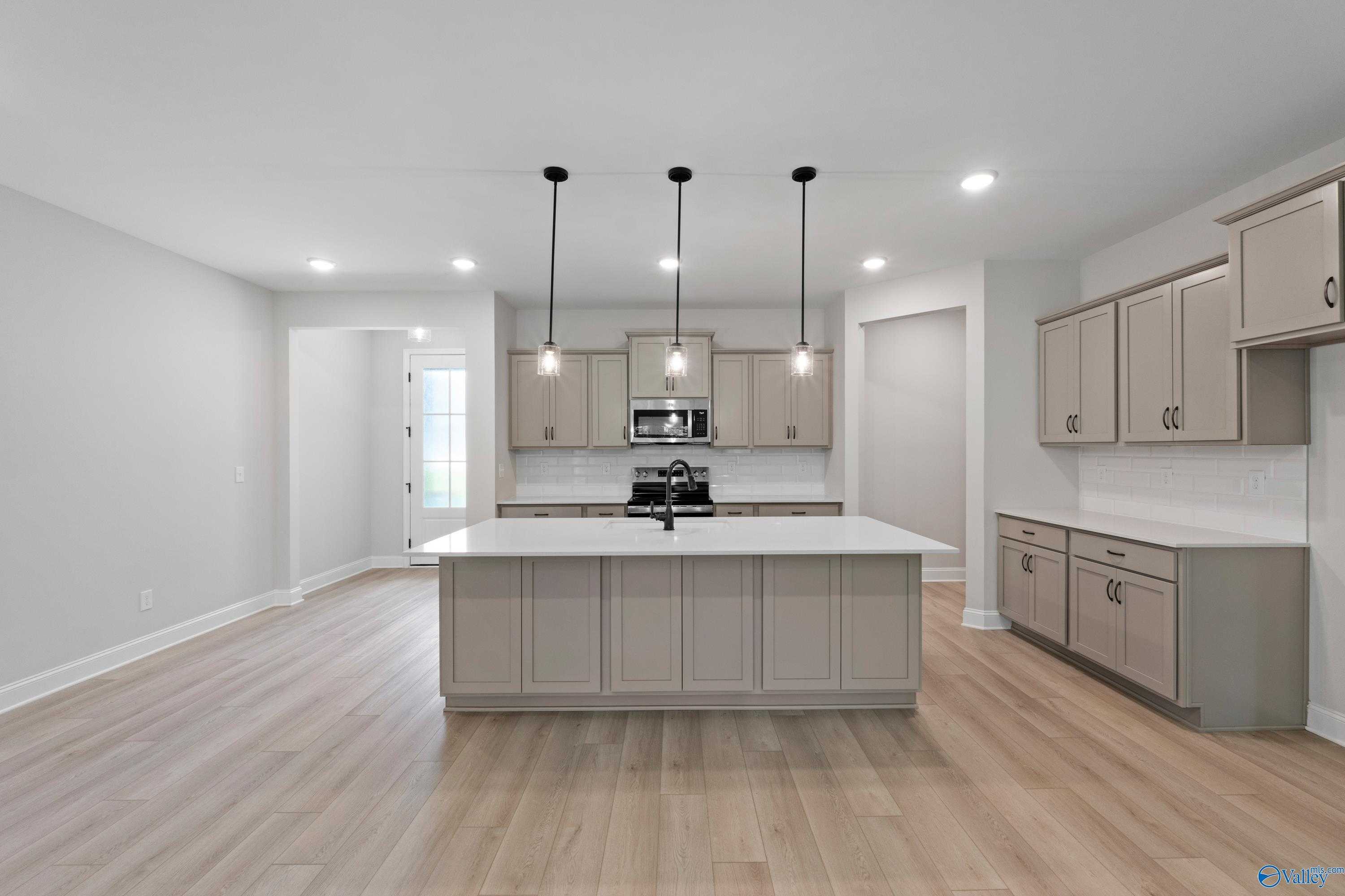 Modern open-concept kitchen with white island, stainless steel appliances, and pendant lights in Davidson Homes The Kirkland, Harvest, AL