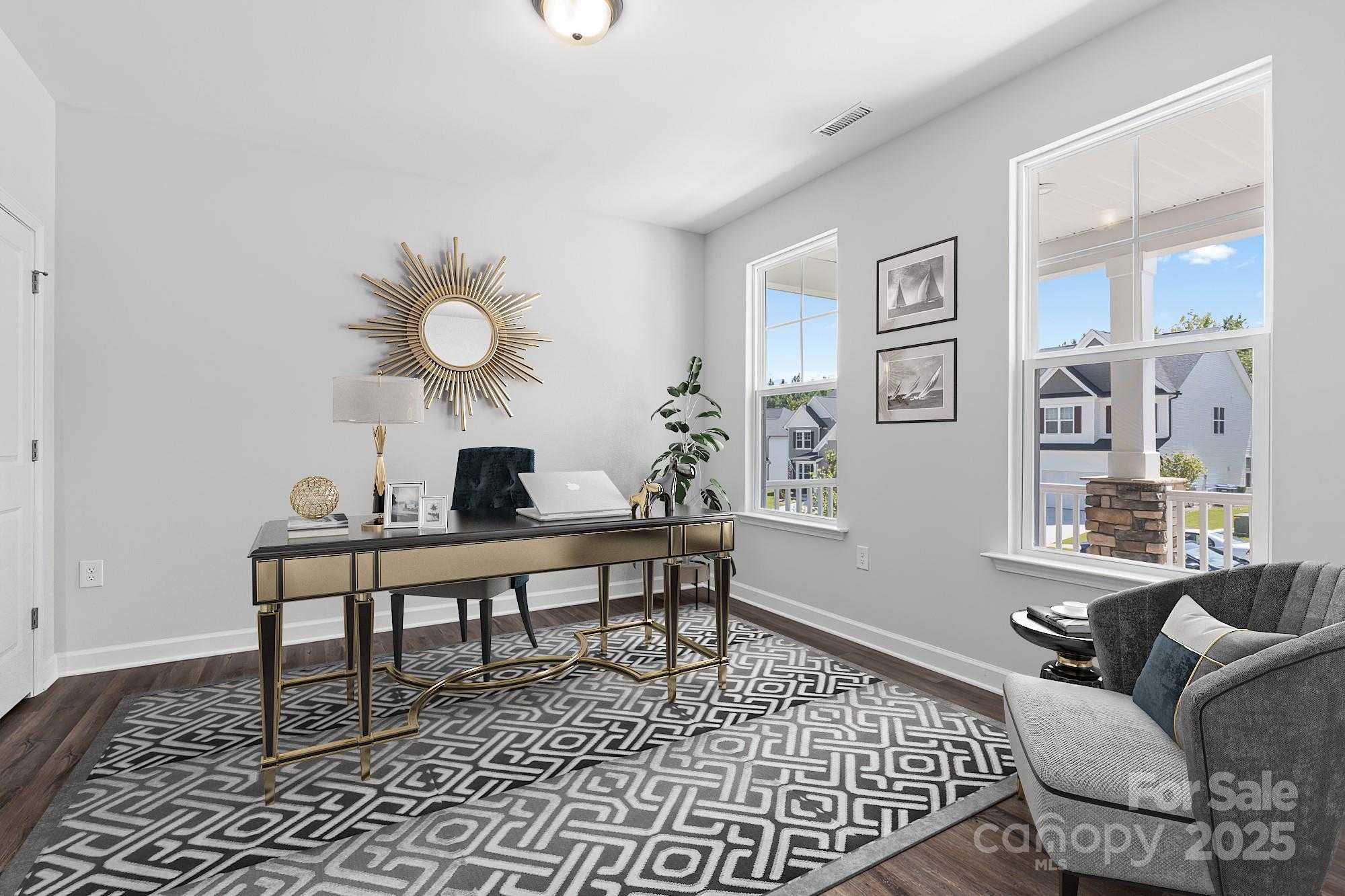 Elegant home office with gold sunburst mirror, brass desk, laptop, and large windows in Davidson Homes The Hemlock A, Belmont, NC