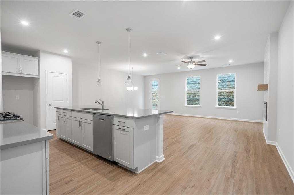 Modern white kitchen with island sink, dishwasher, and open hardwood living area in Davidson Homes Cary A, Kennesaw, Georgia