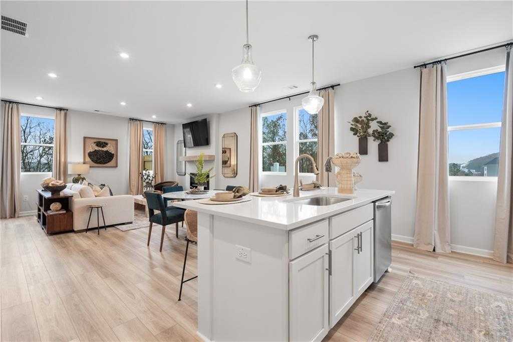 Open-concept living room and kitchen with white island, pendant lights, and large windows in Davidson Homes The Wilmington B, Emerson, Georgia