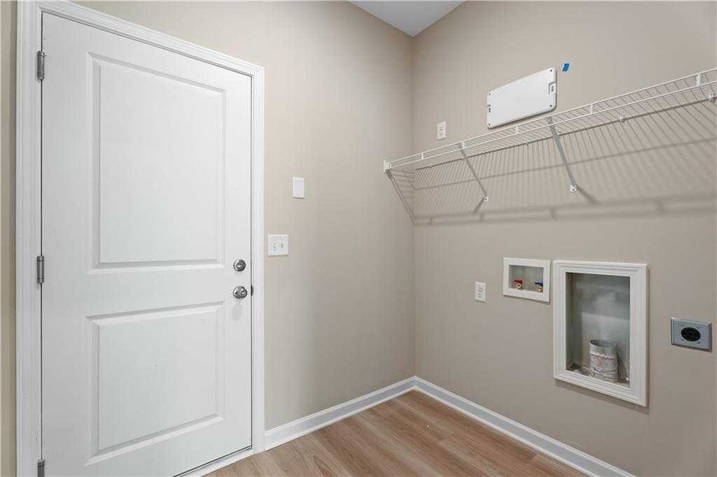 Functional laundry room with white double doors, wire shelving, recessed storage in Davidson Homes The Bartlett, Phenix City, Alabama