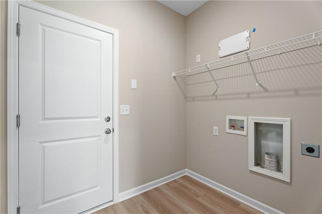 Functional laundry room with white double doors, wire shelving, recessed storage in Davidson Homes The Bartlett, Phenix City, Alabama